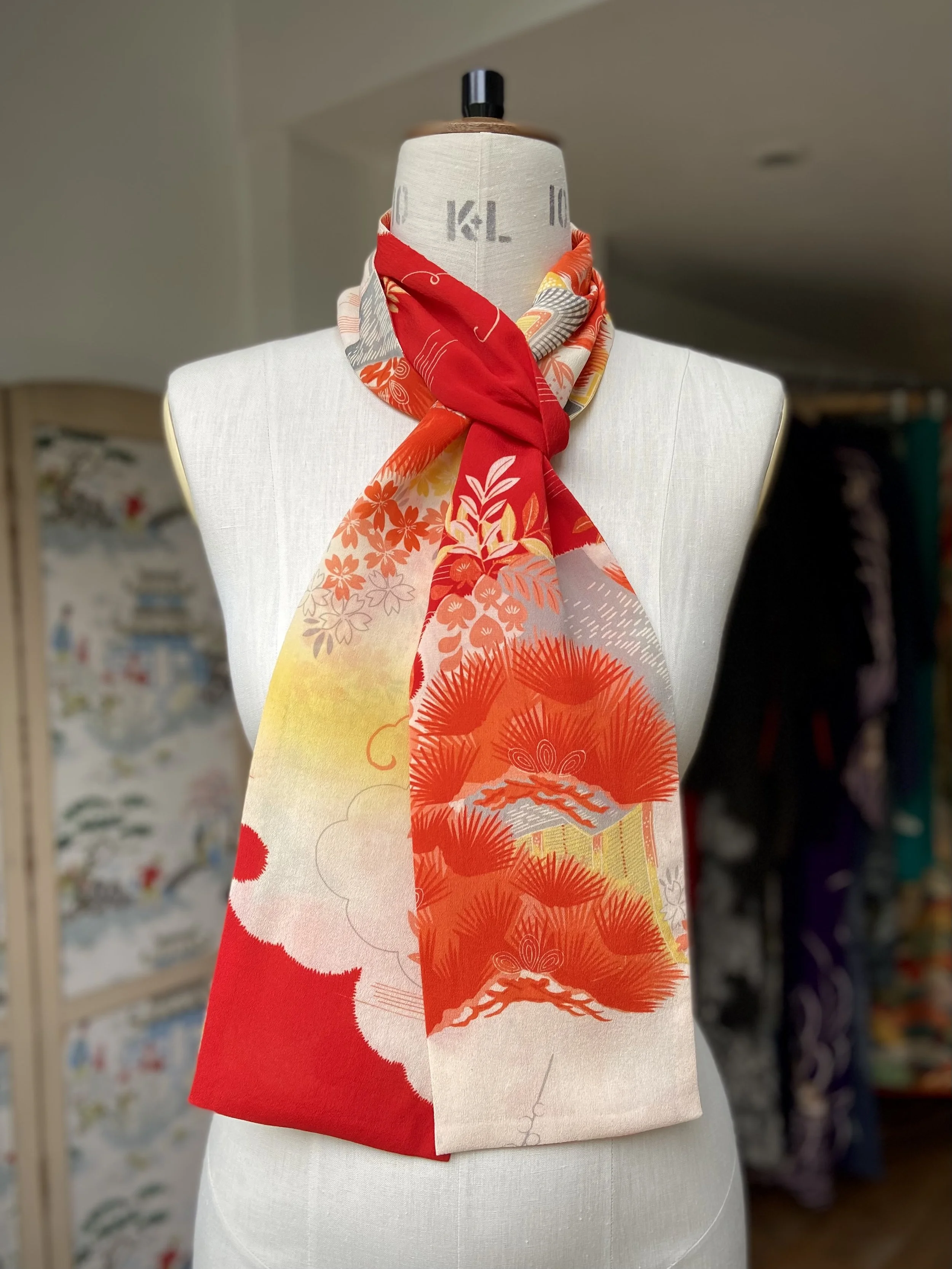 Bright vermillion red and yellow scarf presented on a dress stand, with printed blossom design, handmade from repurposed Japanese kimono crepe silk by Kirsty Chivers
