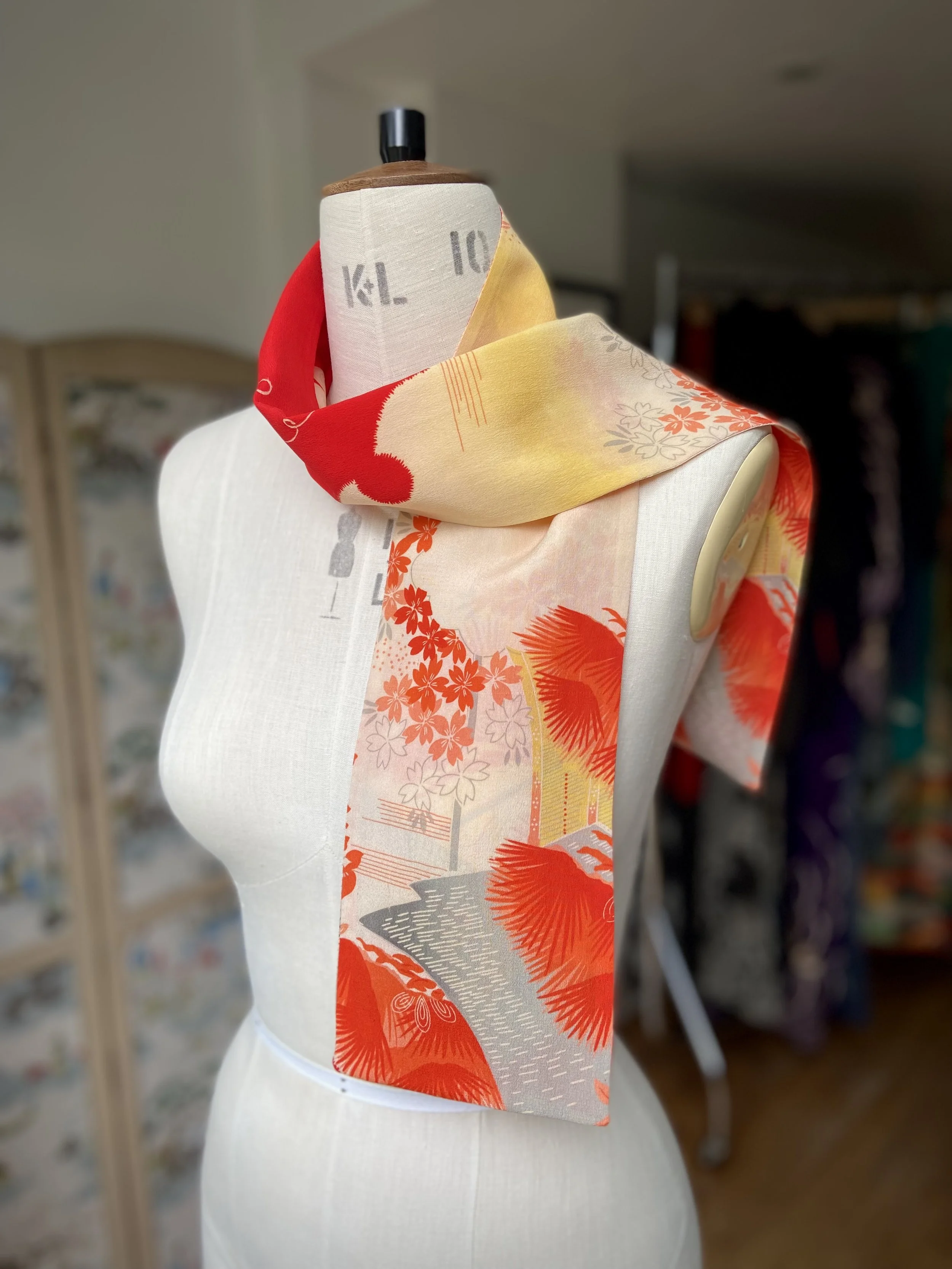 Bright vermillion red and yellow scarf presented on a dress stand, with printed blossom design, handmade from repurposed Japanese kimono crepe silk by Kirsty Chivers