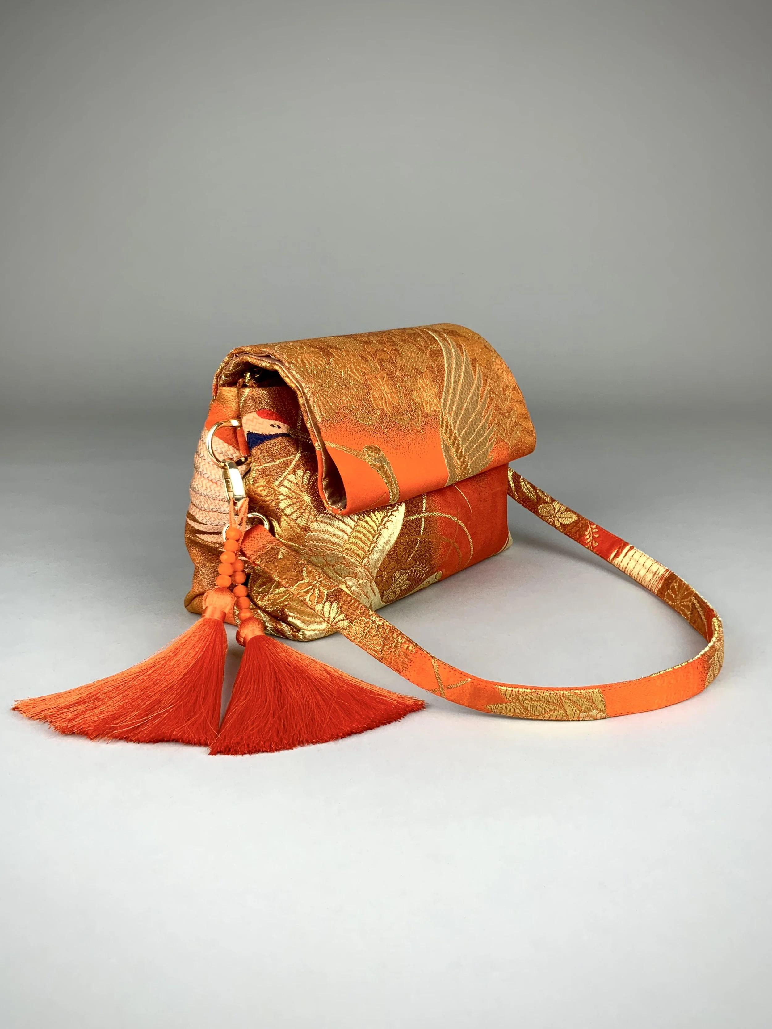 Vibrant orange evening bag with gold copper crane and blossom design, handmade from vintage obi silk by Kirsty Chivers