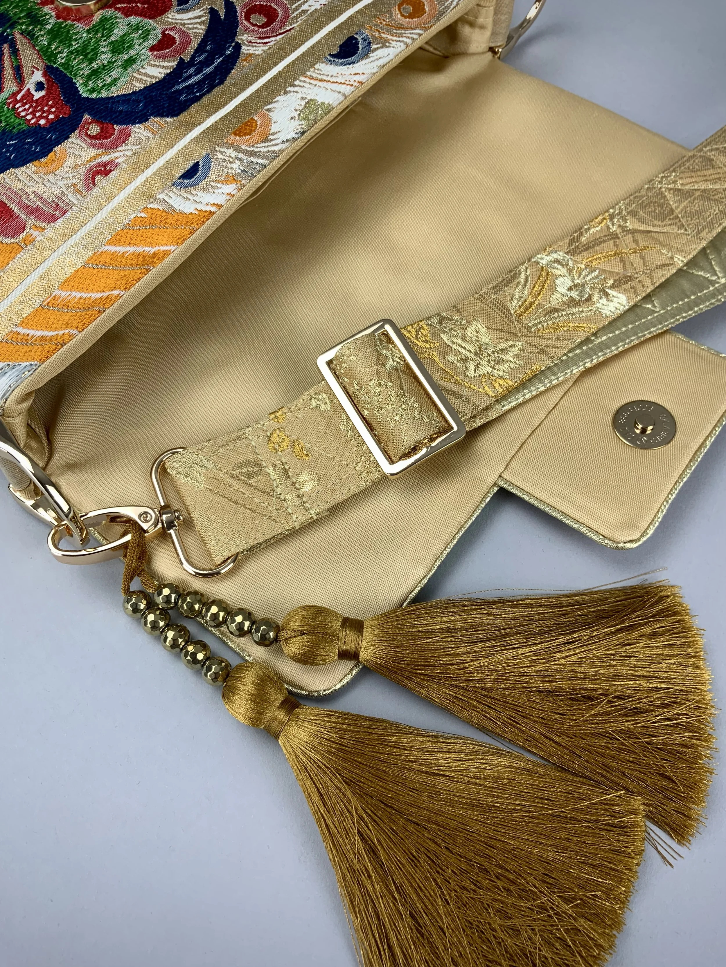 Closeup of one-of-a-kind evening bag in vintage obi silk with peacock, pine motifs & gold accents