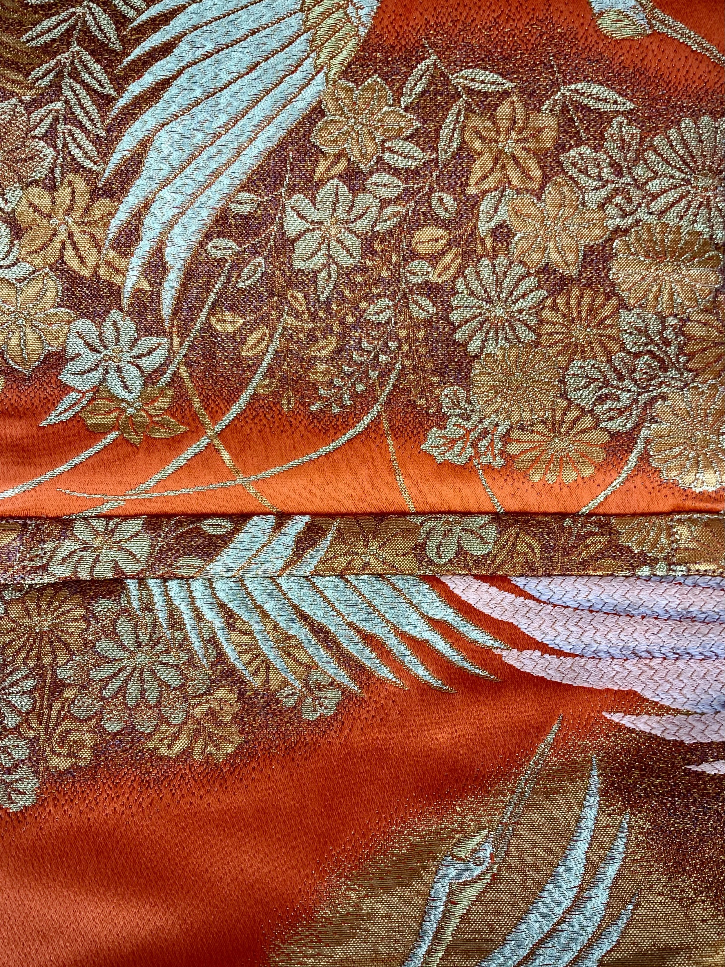 Closeup of vibrant orange evening bag with gold copper crane and blossom design, handmade from vintage obi silk by Kirsty Chivers