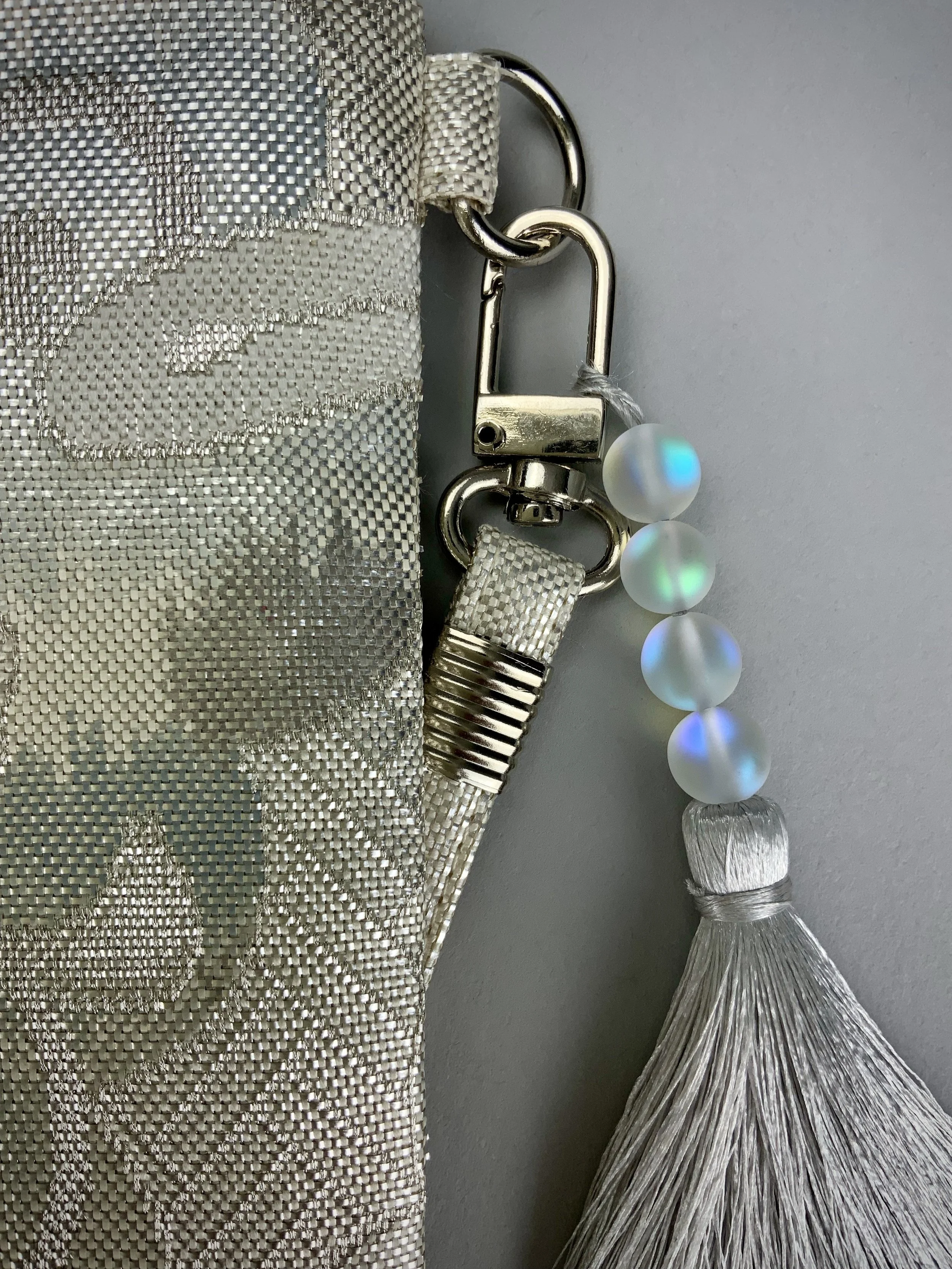 Closeup of silver clutch purse with tassel and moonstone beads, made from vintage Japanese obi silk