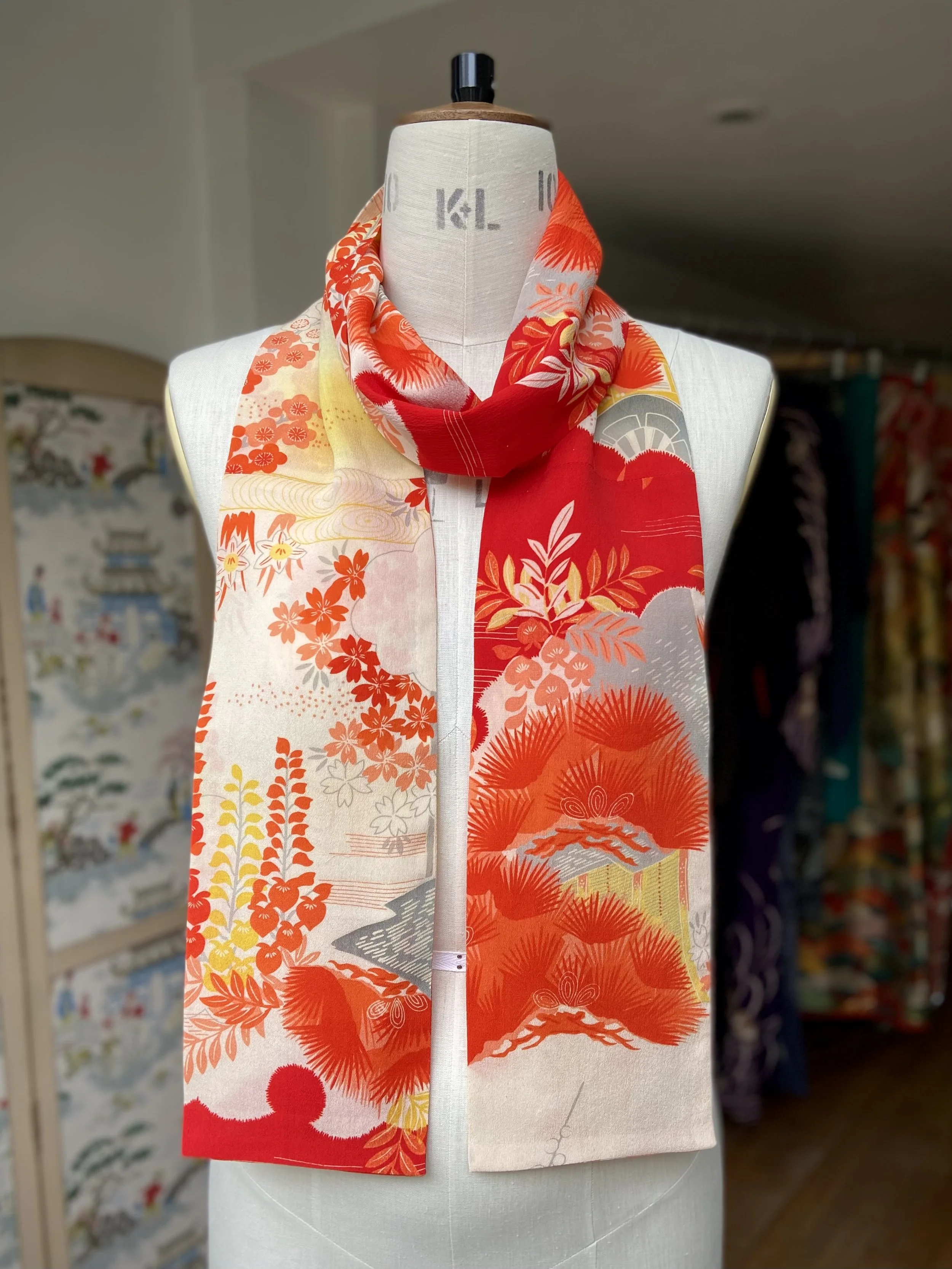 Bright vermillion red and yellow scarf presented on a dress stand, with printed blossom design, handmade from repurposed Japanese kimono crepe silk by Kirsty Chivers