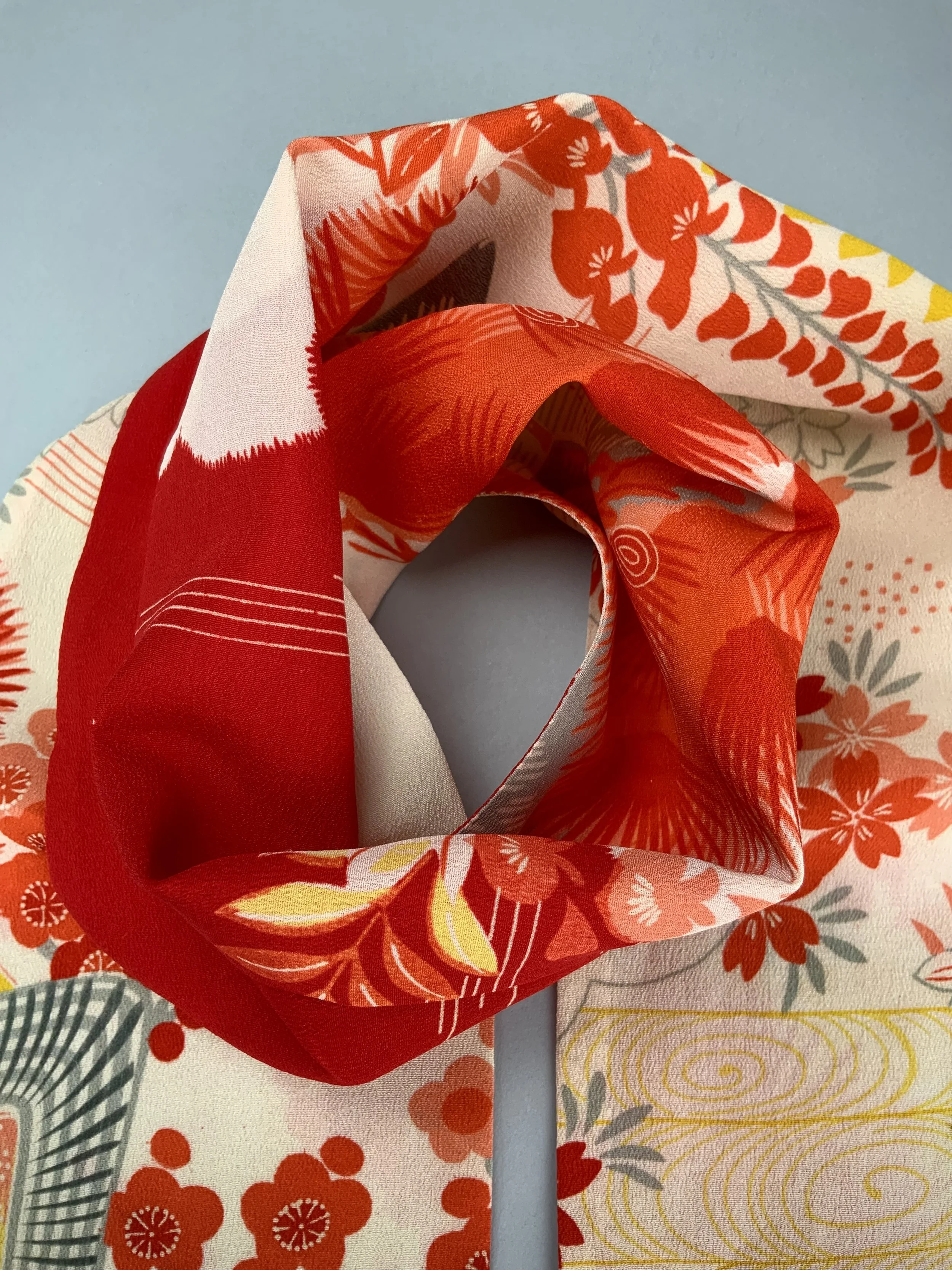 Closeup of vibrant red and yellow scarf with printed blossom design, handmade from repurposed Japanese kimono crepe silk by Kirsty Chivers