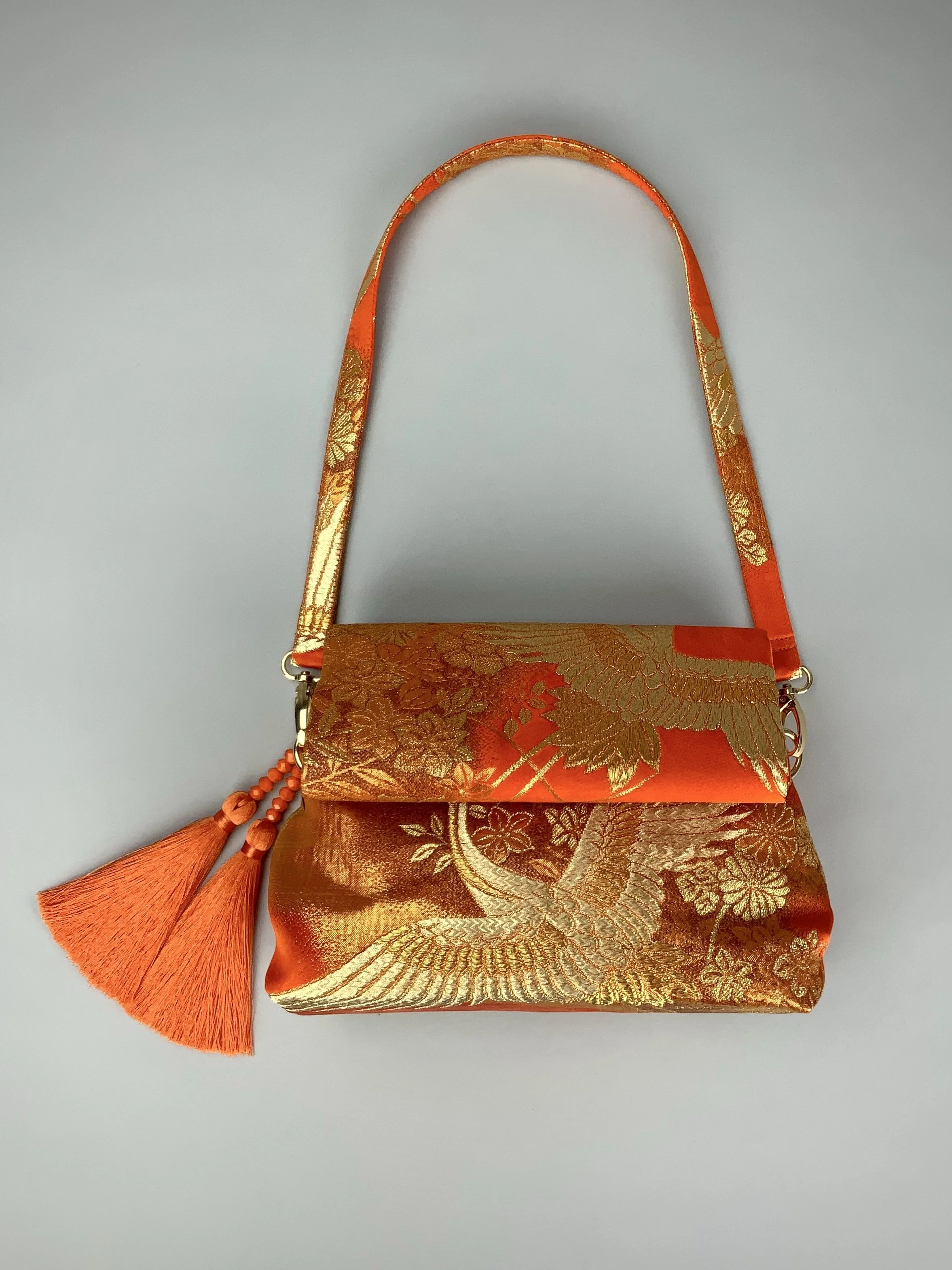Vibrant orange evening bag with gold copper crane and blossom design, handmade from vintage obi silk by Kirsty Chivers