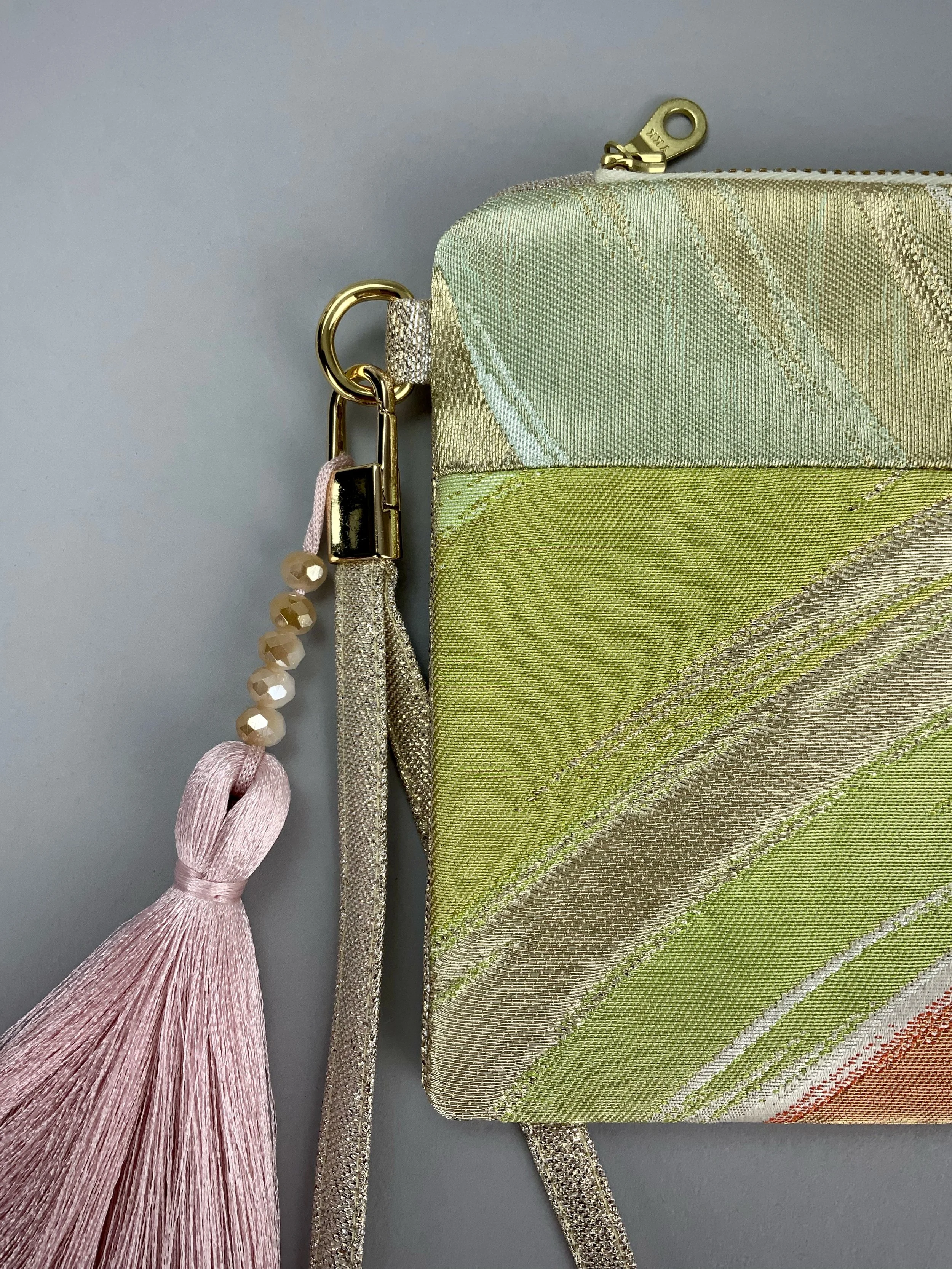 Closeup up wristlet purse made from repurposed vintage obi fabric with brushstroke pastel design and gold-silver threads