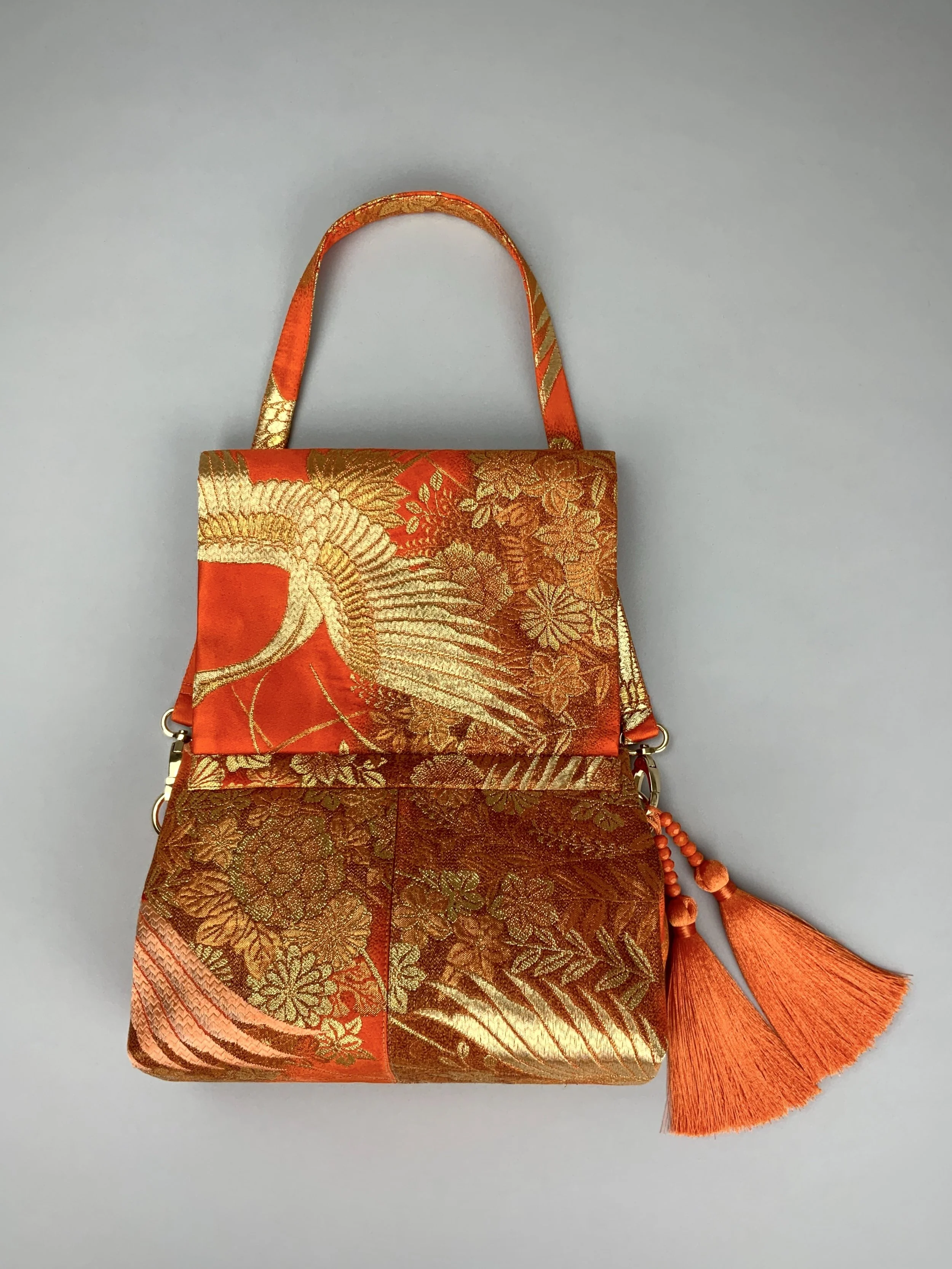 Vibrant orange evening bag with gold copper crane and blossom design, handmade from vintage obi silk by Kirsty Chivers