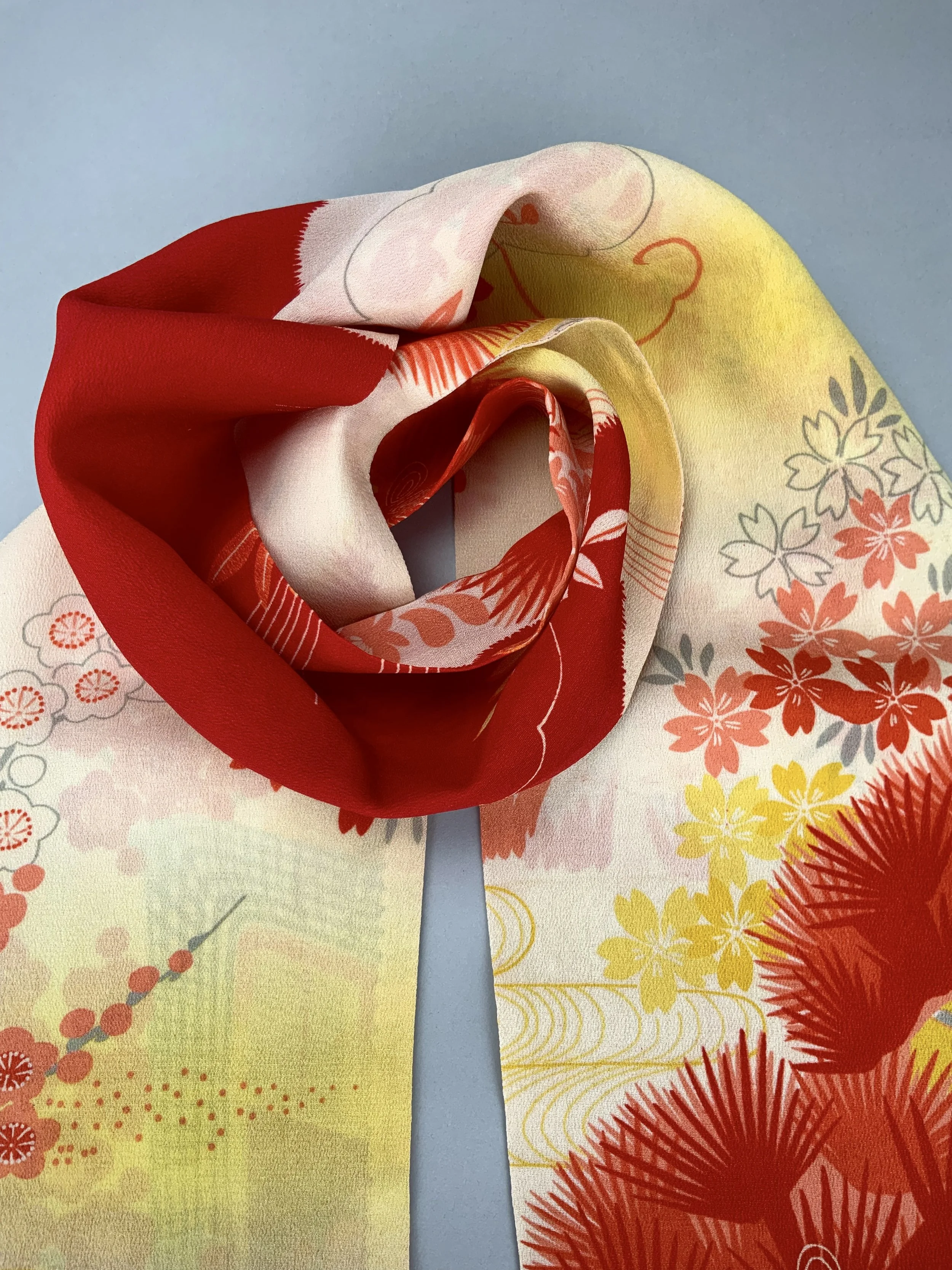 Closeup of vibrant red and yellow scarf with printed blossom design, handmade from repurposed Japanese kimono crepe silk by Kirsty Chivers