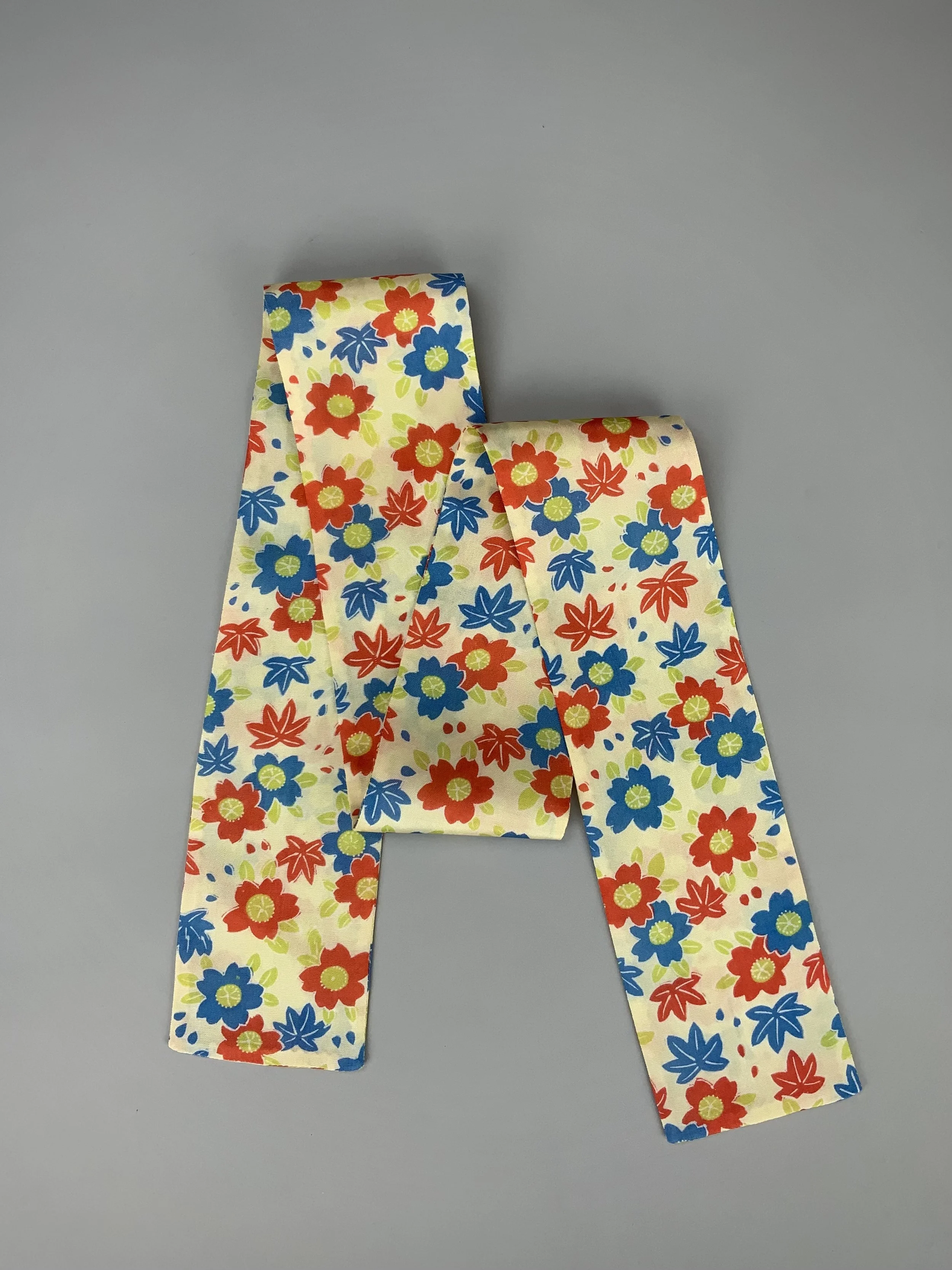 Flatlay of butter yellow skinny scarf with Cherry blossom & Maple leaf print, handmade by Kirsty Chivers