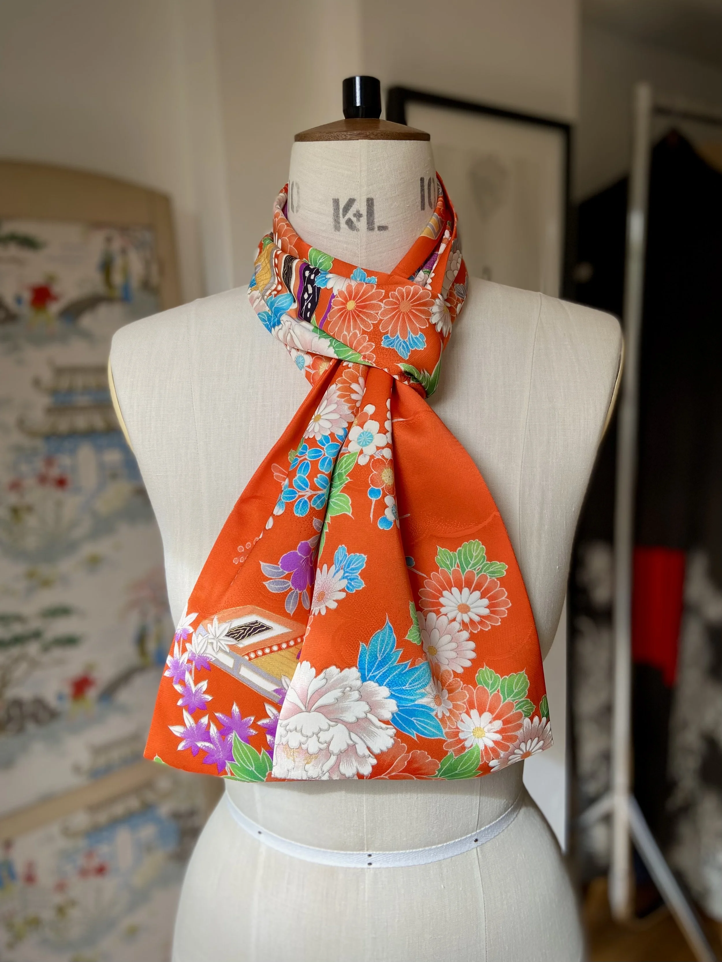Orange scarf presented on a dress stand. It has a blossom print and is made from rinzu kimono silk by Kirsty Chivers