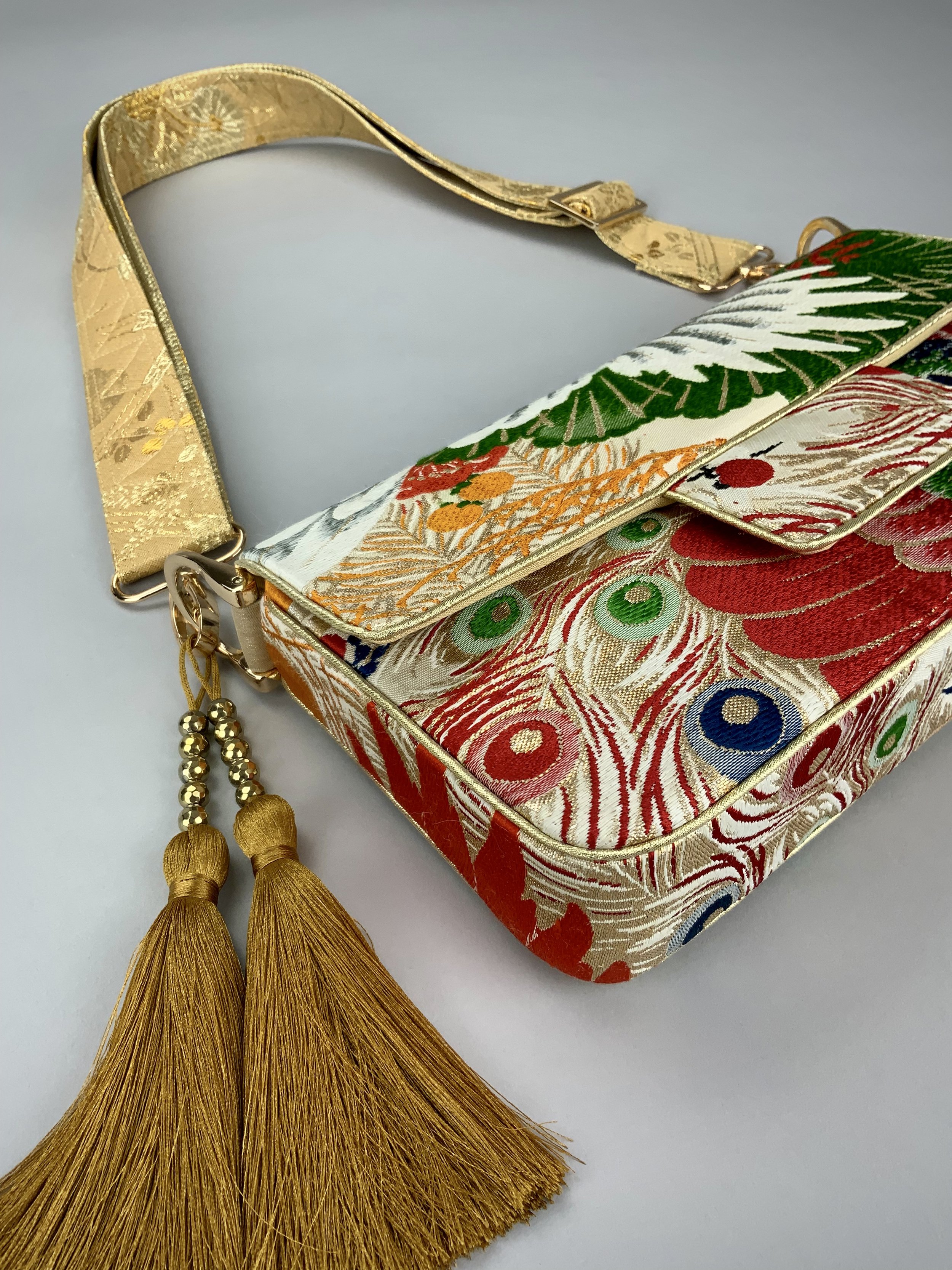 Closeup of one-of-a-kind evening bag in vintage obi silk with peacock, pine motifs & gold accents