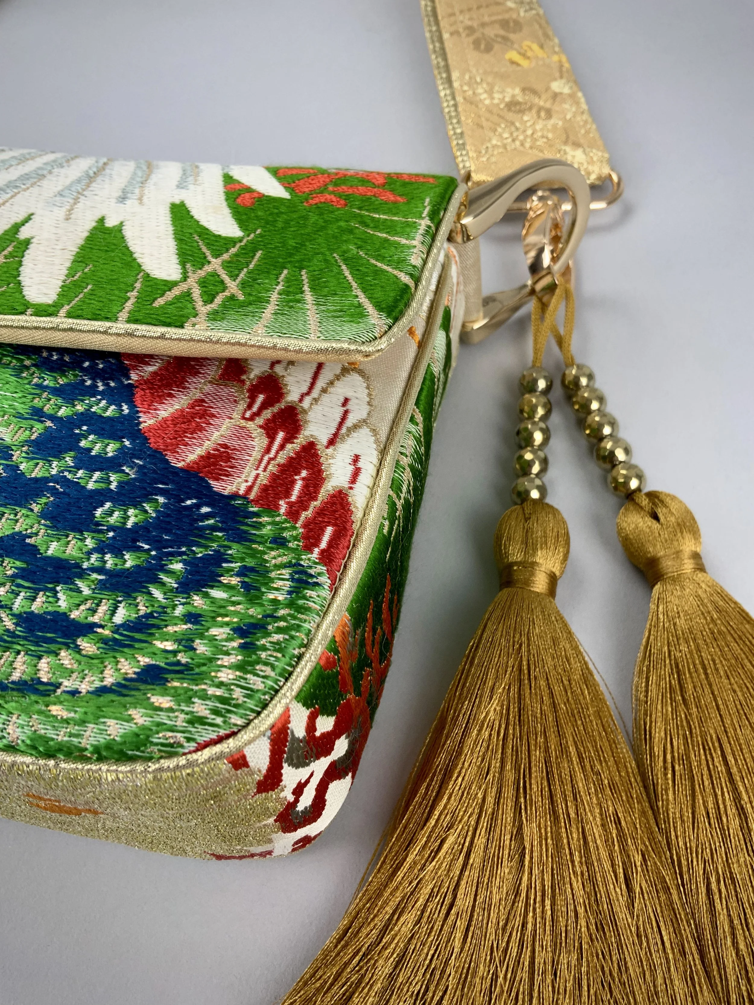 Closeup of one-of-a-kind evening bag in vintage obi silk with peacock, pine motifs & gold accents