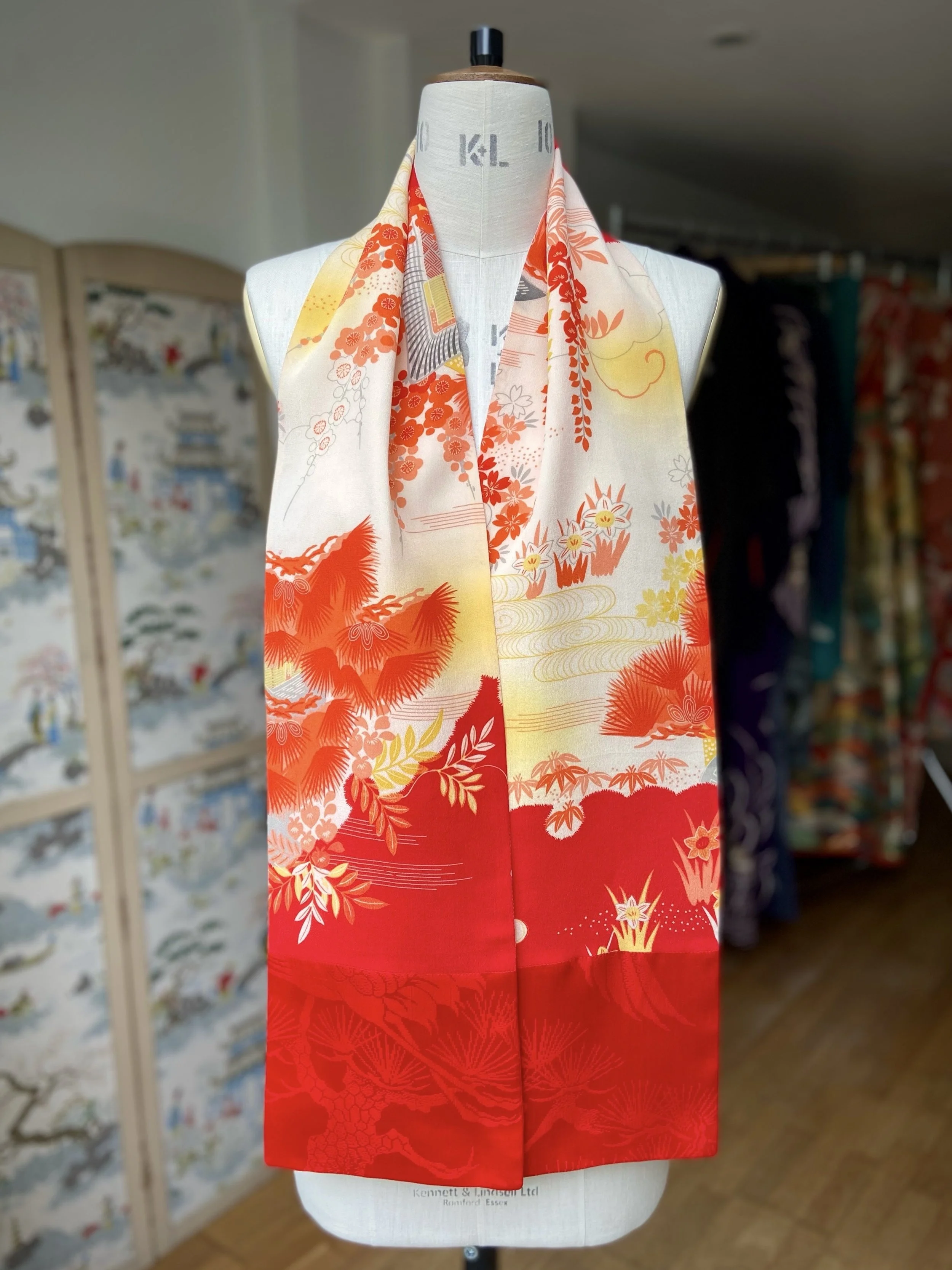Bright vermillion red and yellow scarf presented on a dress stand, with printed blossom design, handmade from repurposed Japanese kimono crepe silk by Kirsty Chivers