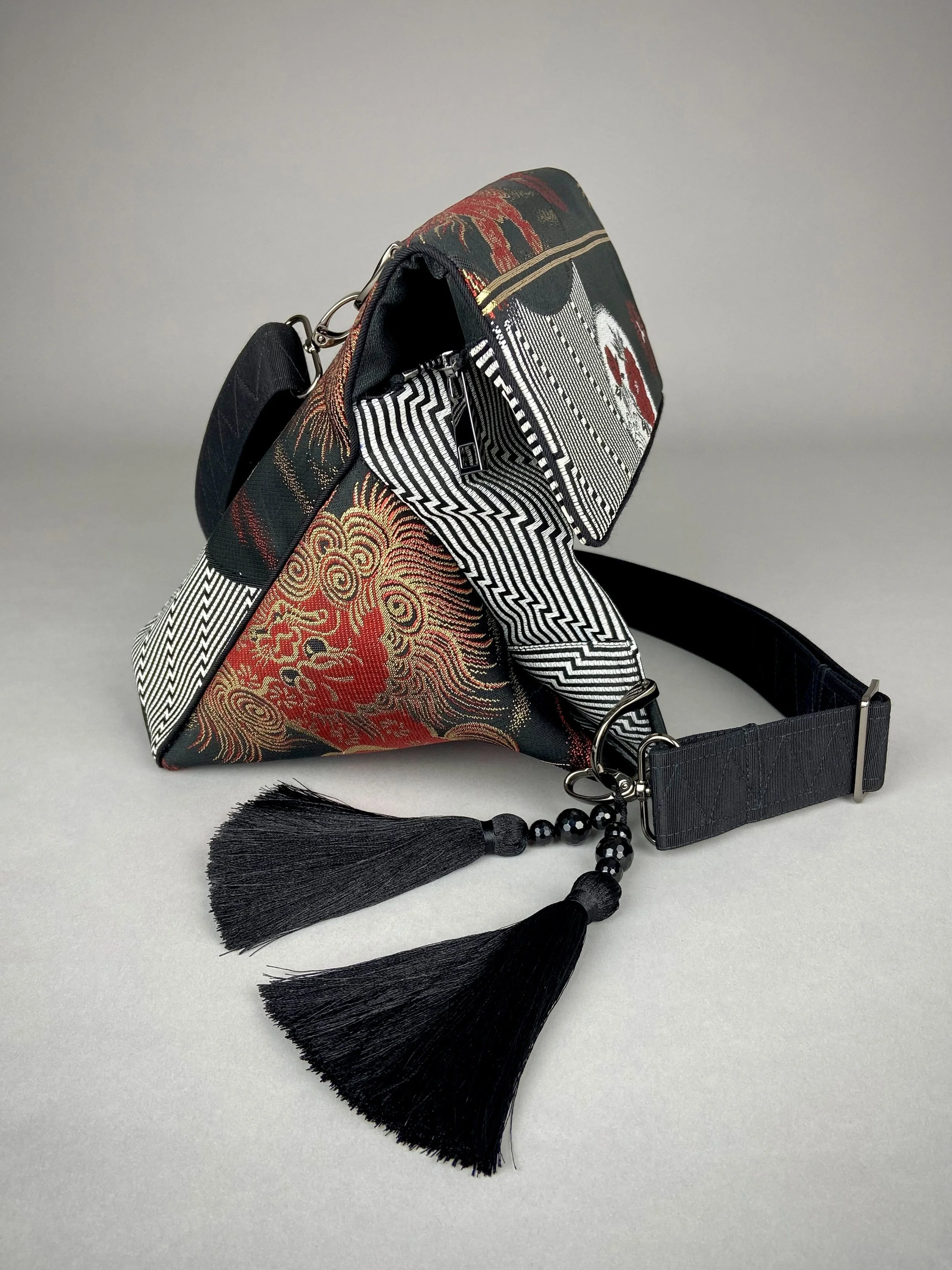 Black matt satin silk and rayon obi bag with red, green, gold and ivory dragon motifs, gunmetal hardware and black tassel charm by Kirsty Chivers