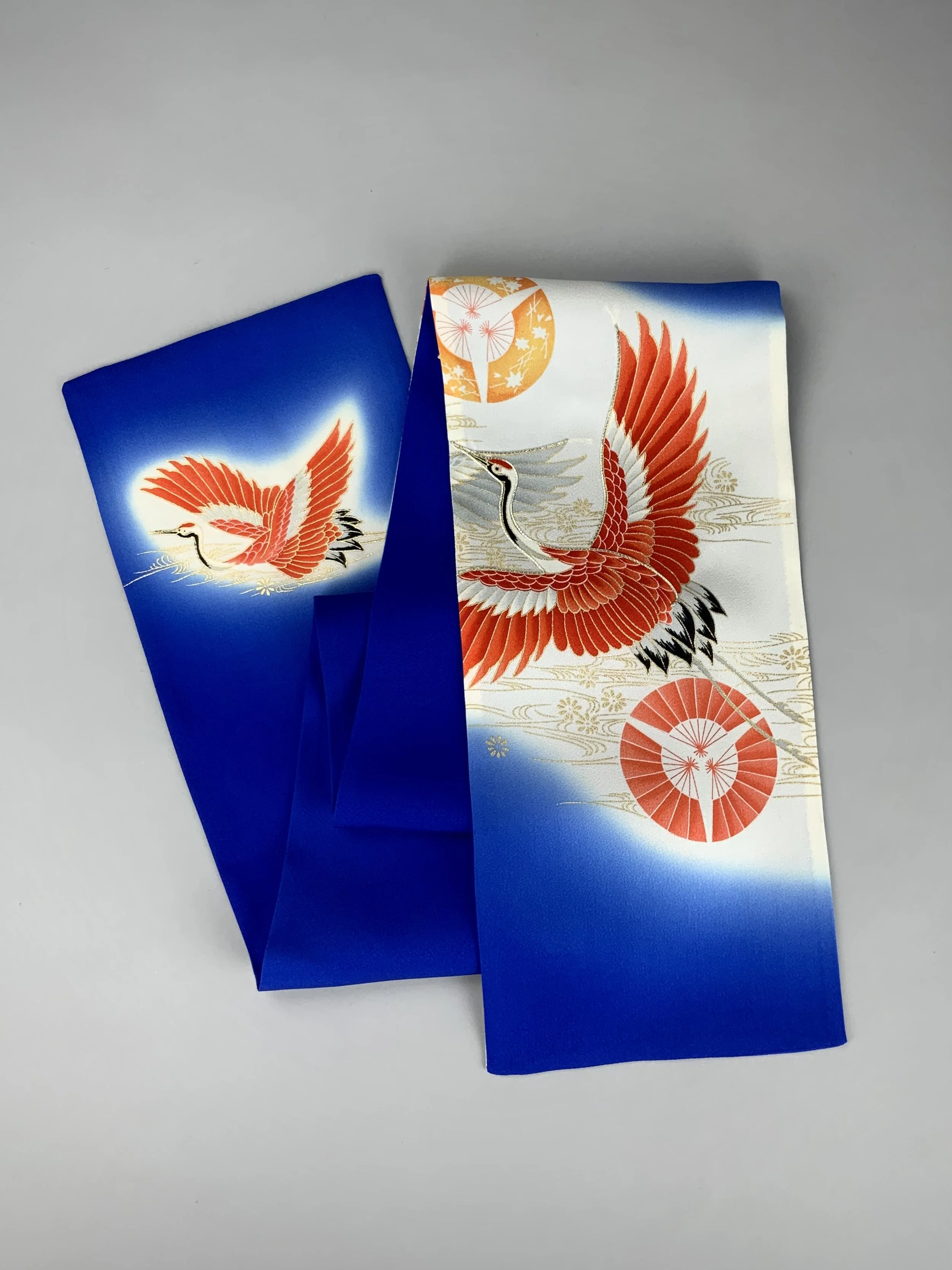 Flatlay of blue silk scarf with printed Flying Crane design handmade by Kirsty Chivers