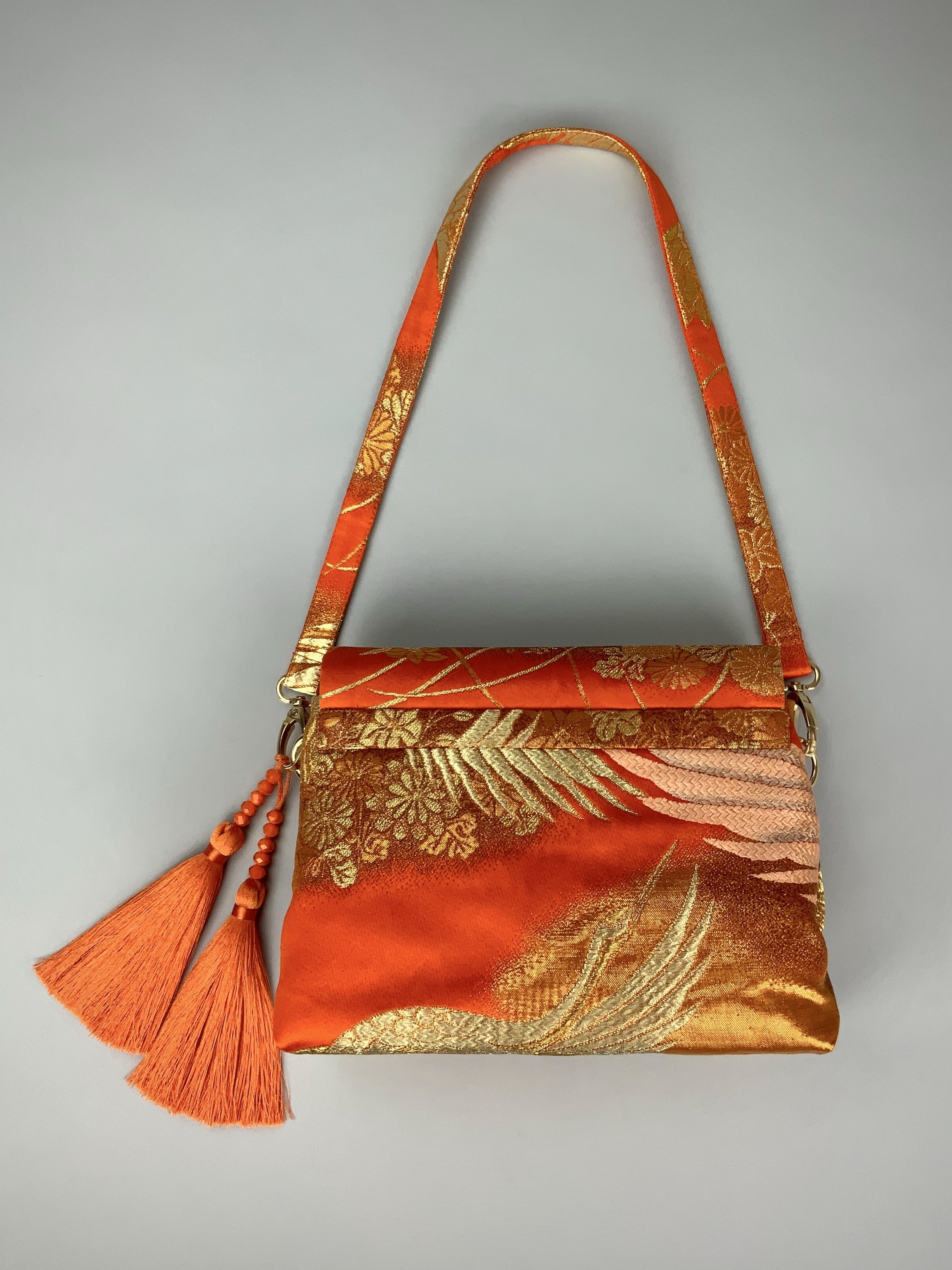 Vibrant orange evening bag with gold copper crane and blossom design, handmade from vintage obi silk by Kirsty Chivers