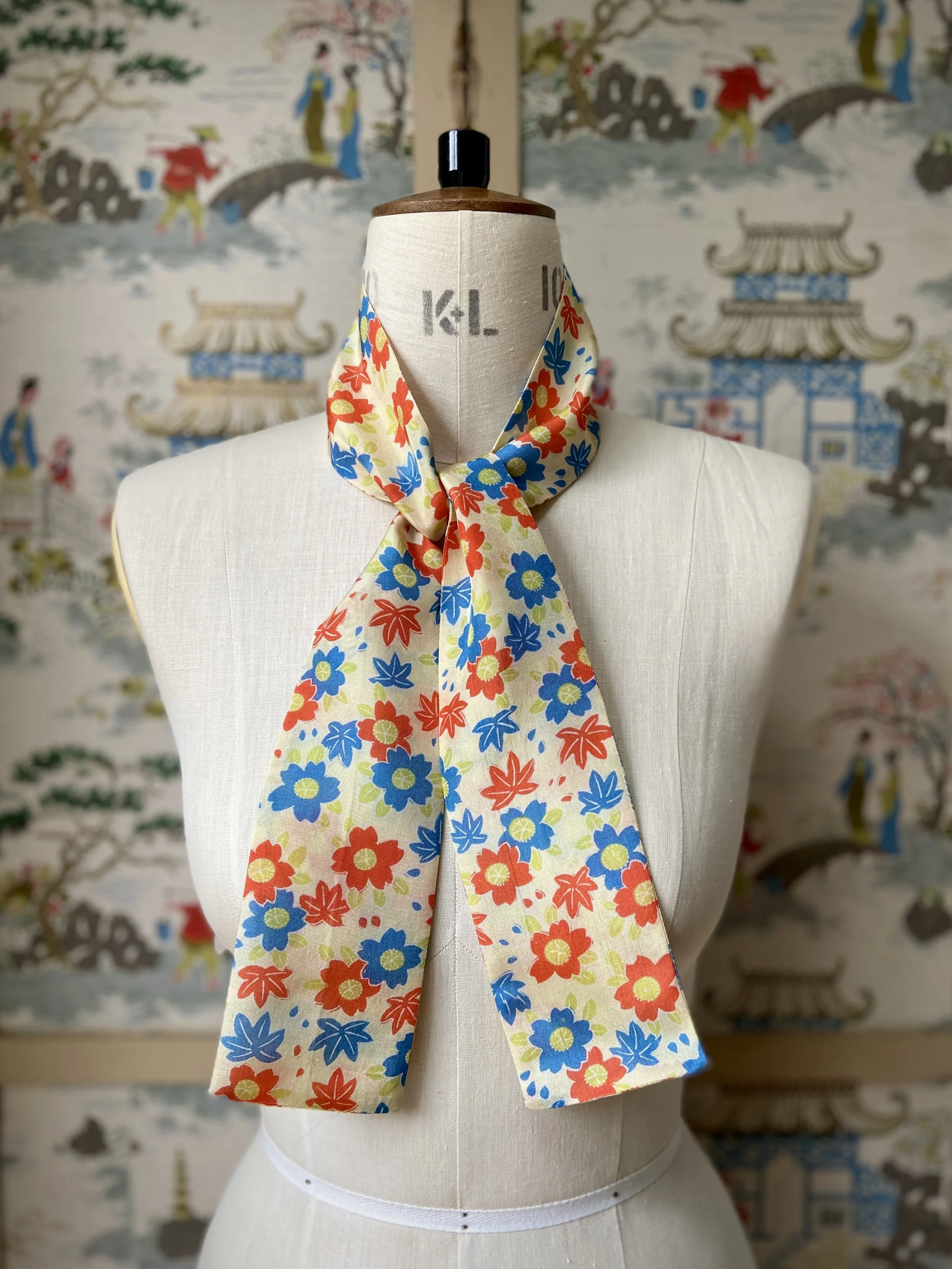 Pale yellow skinny scarf presented on a dress stand, with printed cherry blossom design, handmade from repurposed kimono fabric by Kirsty Chivers