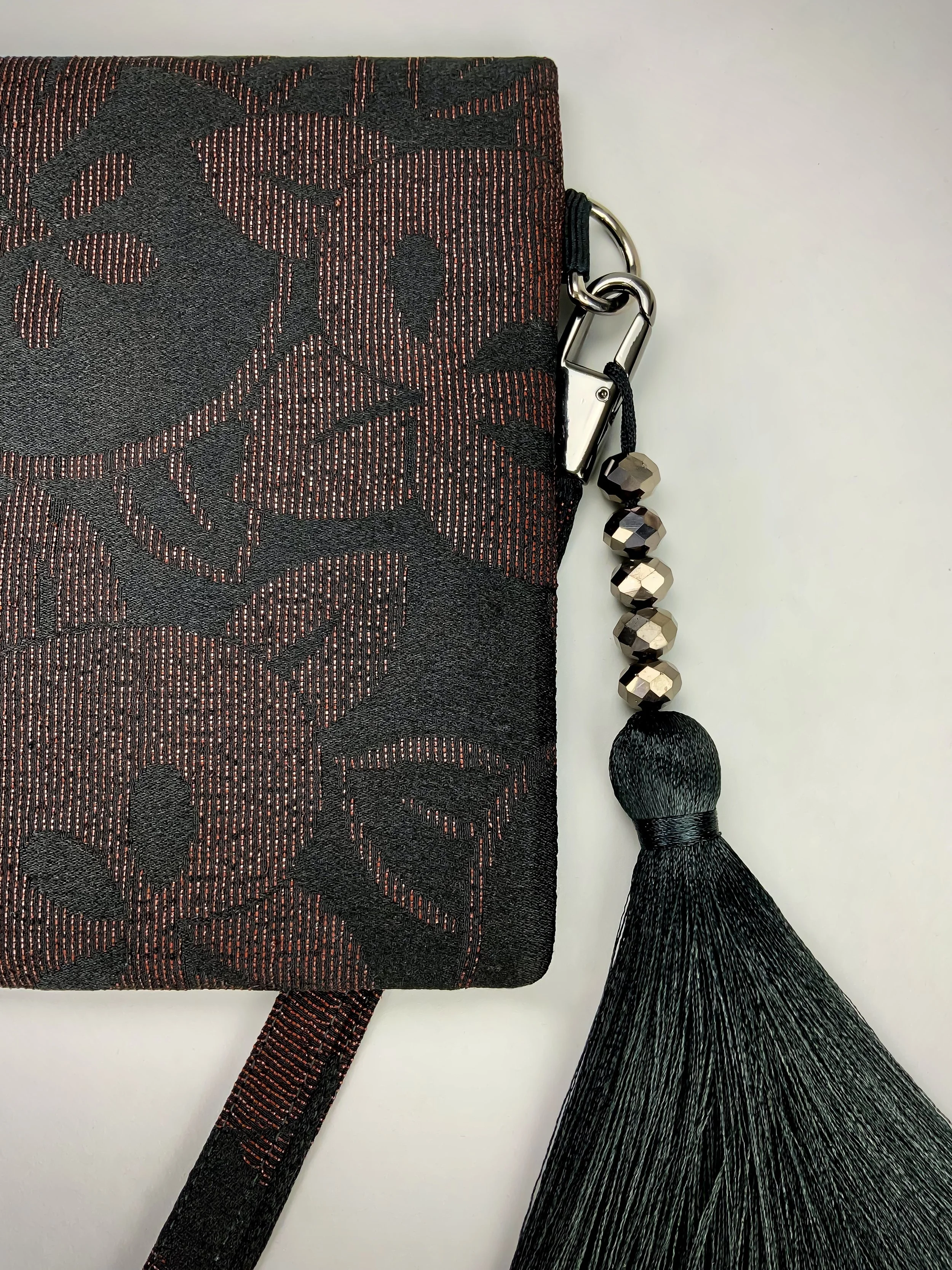 Closeup of glittery black wristlet clutch purse with tassel, handmade from vintage Japanese kimono silk