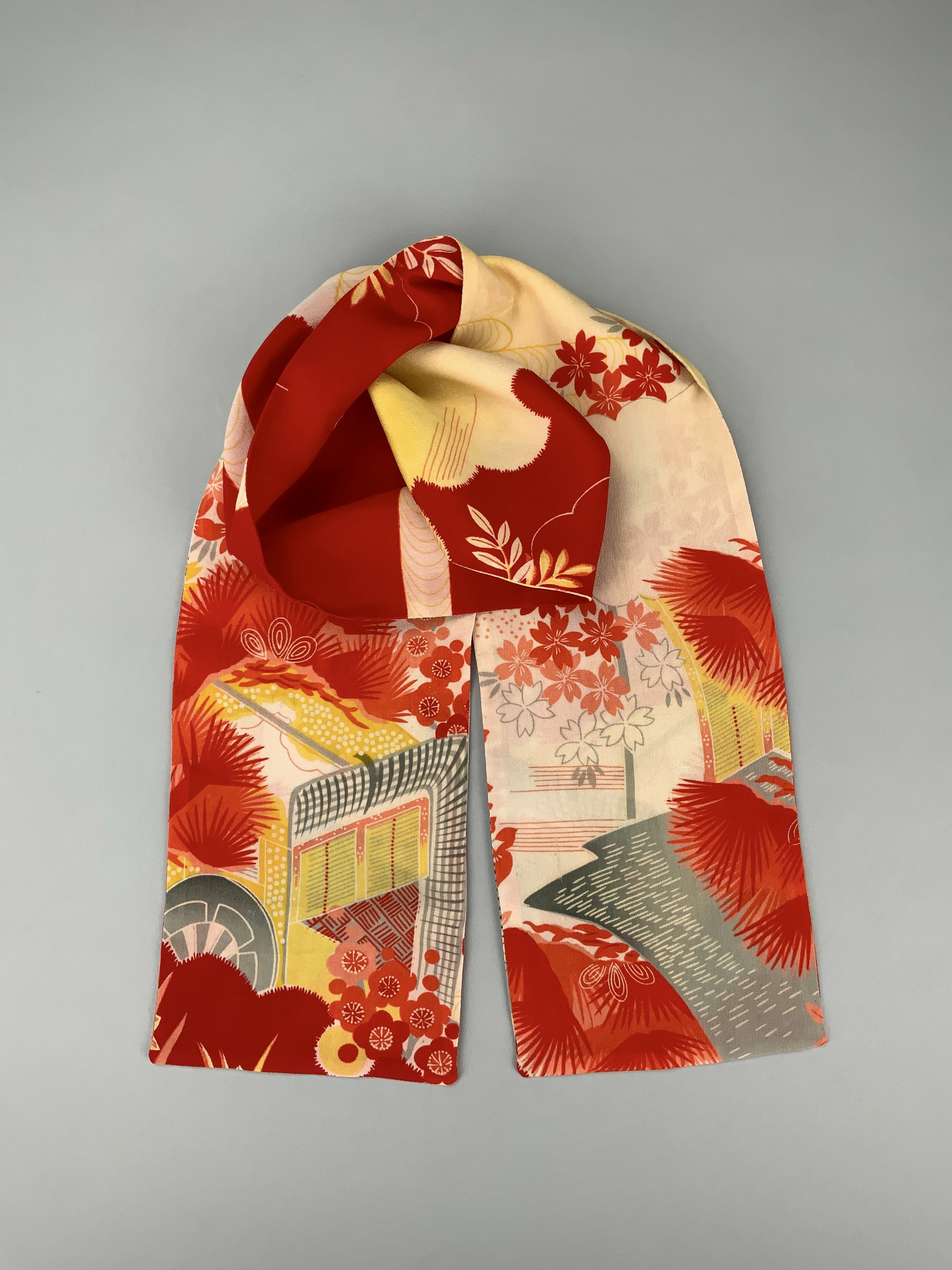 Flatlay of vibrant red and yellow scarf with printed blossom design, handmade from repurposed Japanese kimono crepe silk by Kirsty Chivers