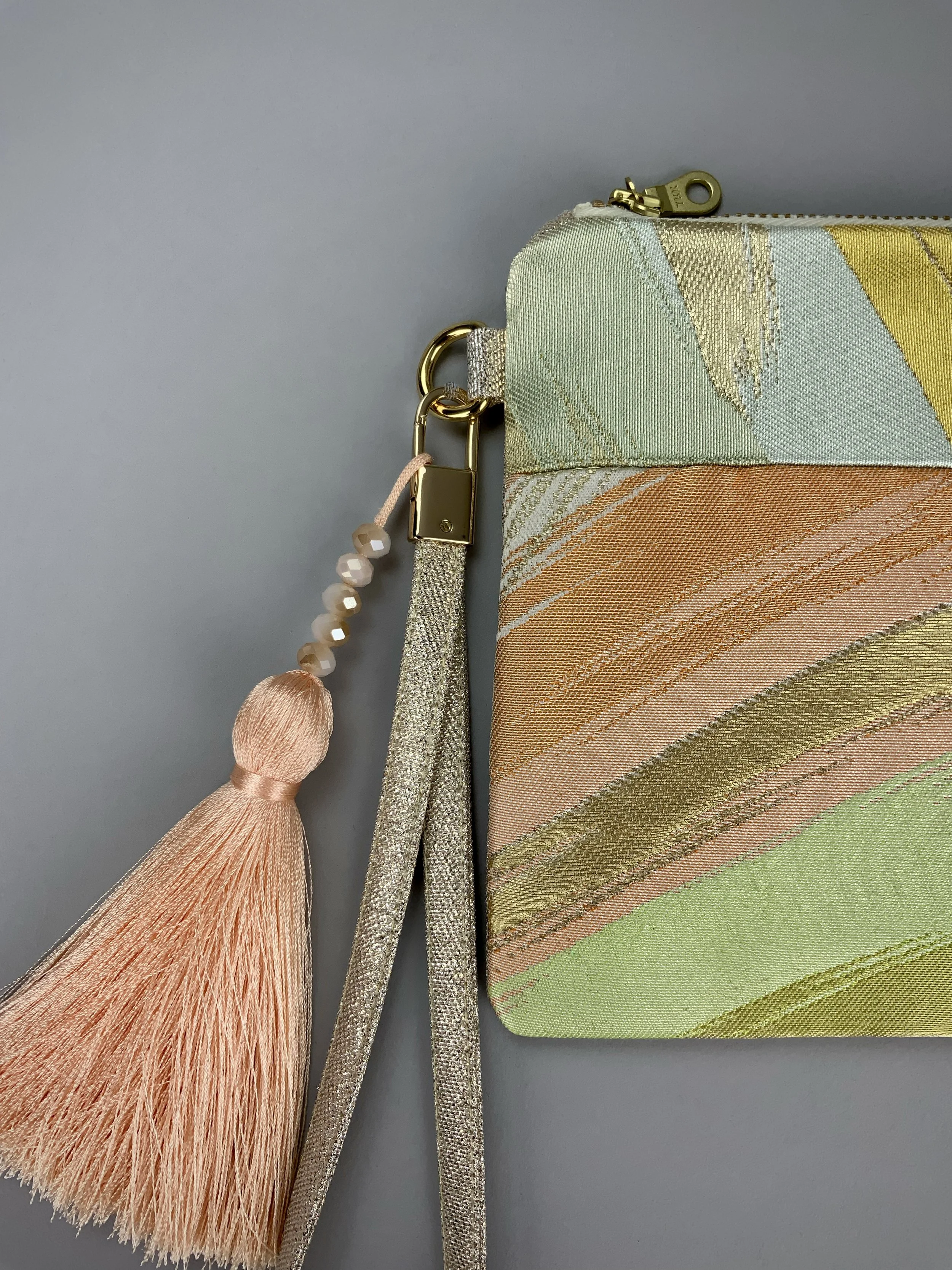 Closeup of wristlet purse made from repurposed vintage obi fabric with brushstroke pastel design and gold-silver threads