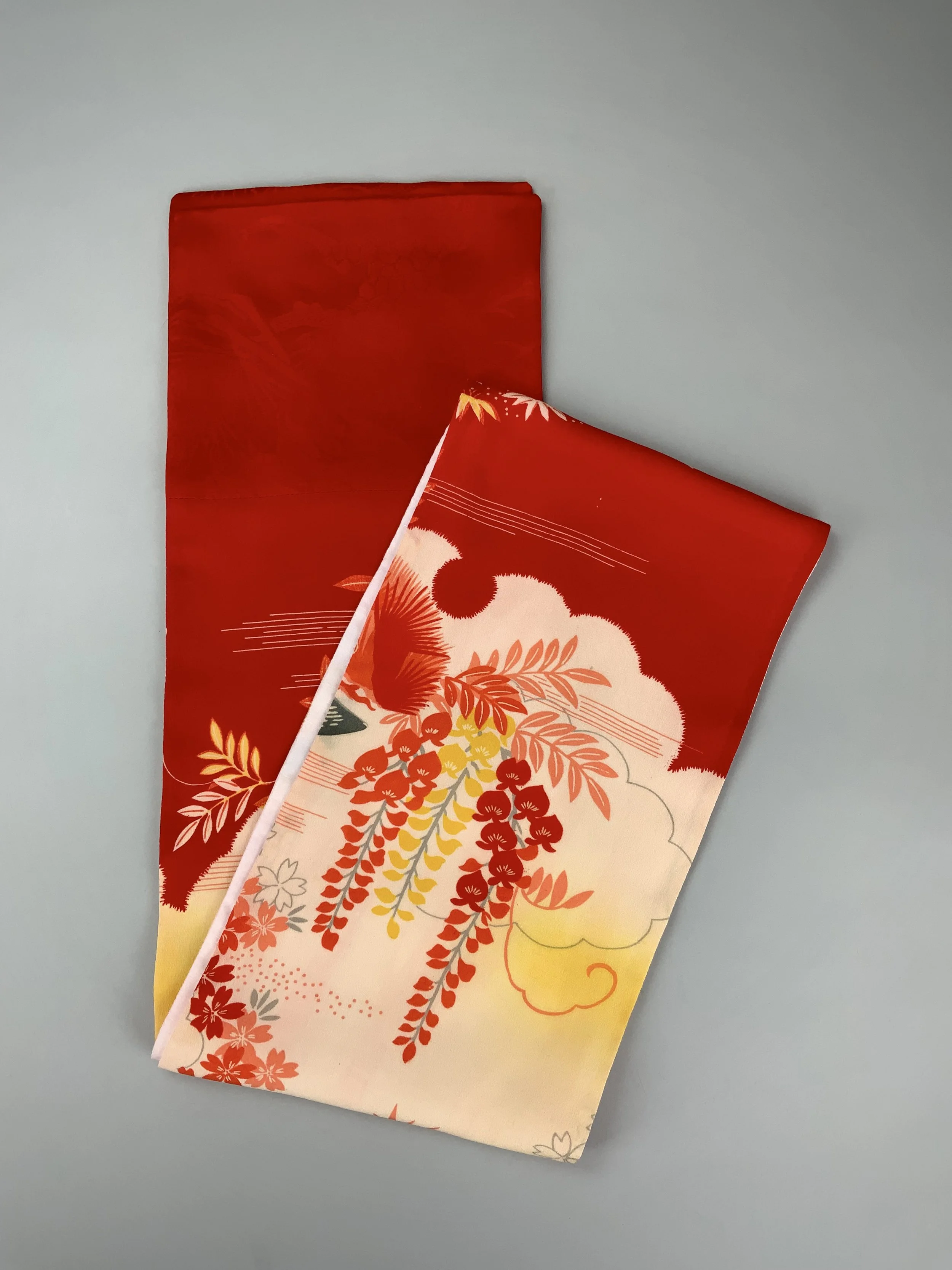 Flatlay showing vibrant red and yellow scarf with printed blossom design, handmade from repurposed Japanese kimono crepe silk by Kirsty Chivers