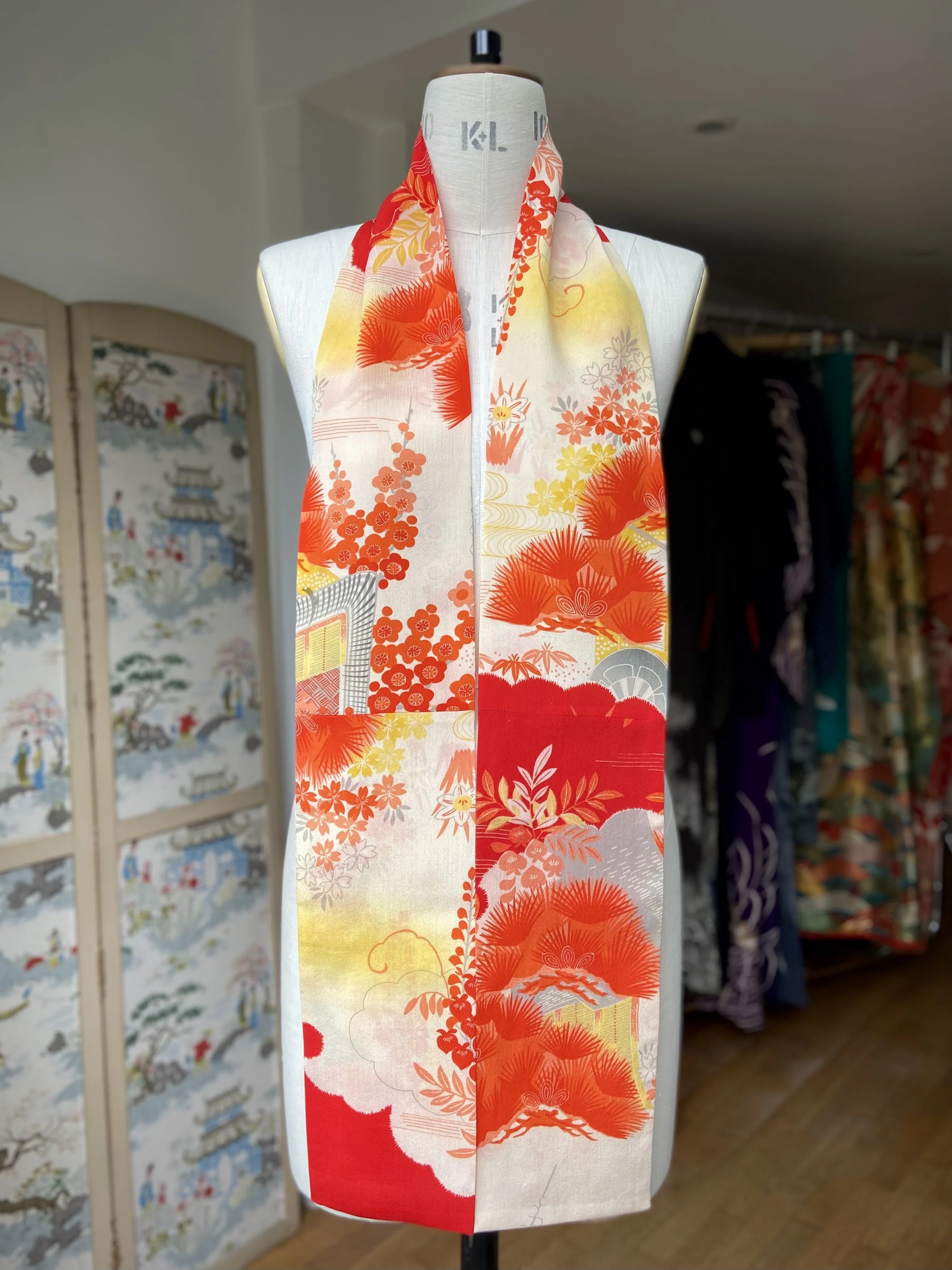 Bright vermillion red and yellow scarf presented on a dress stand, with printed blossom design, handmade from repurposed Japanese kimono crepe silk by Kirsty Chivers