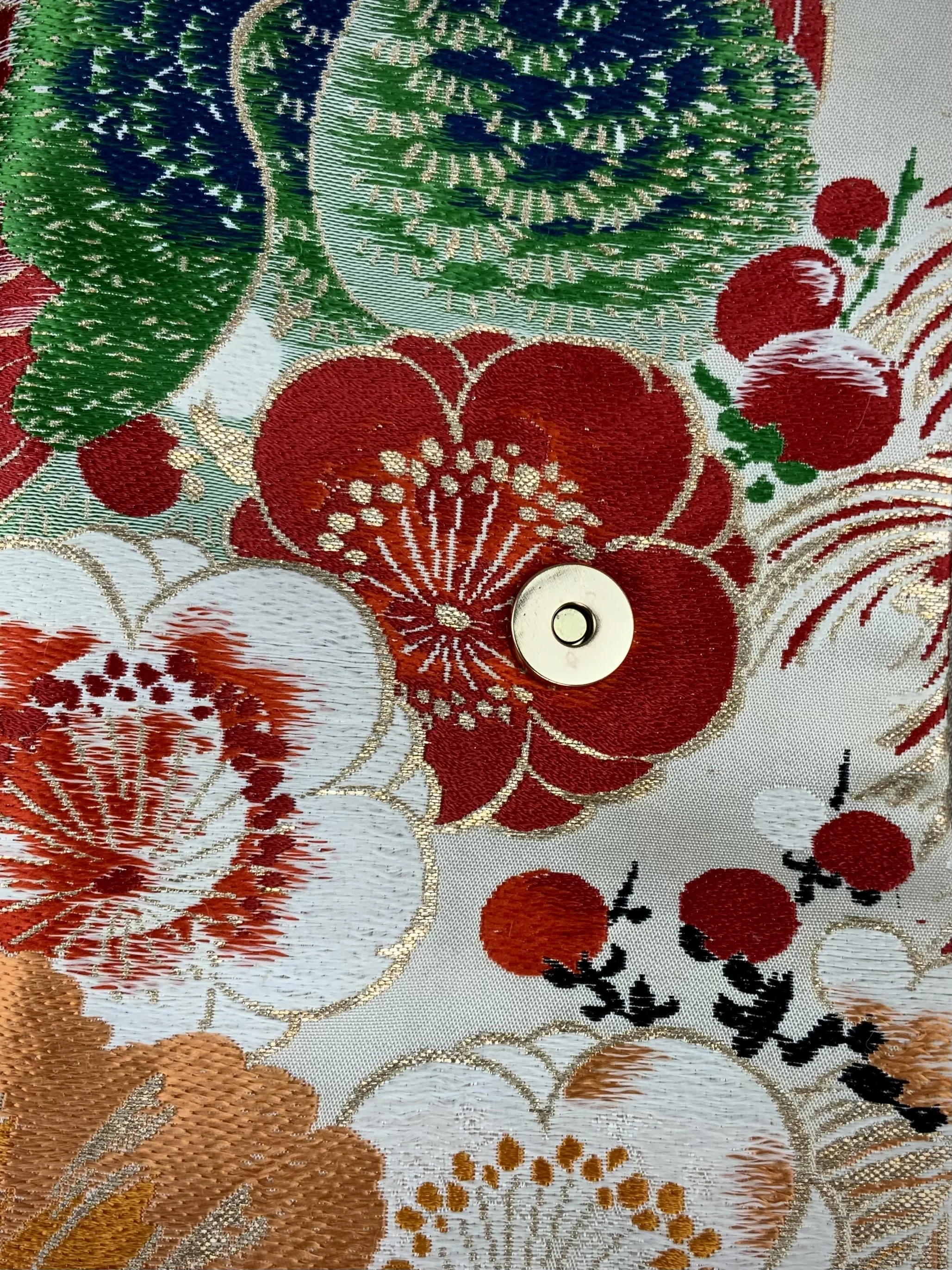 Closeup of one-of-a-kind evening bag in vintage obi silk with peacock, pine motifs & gold accents