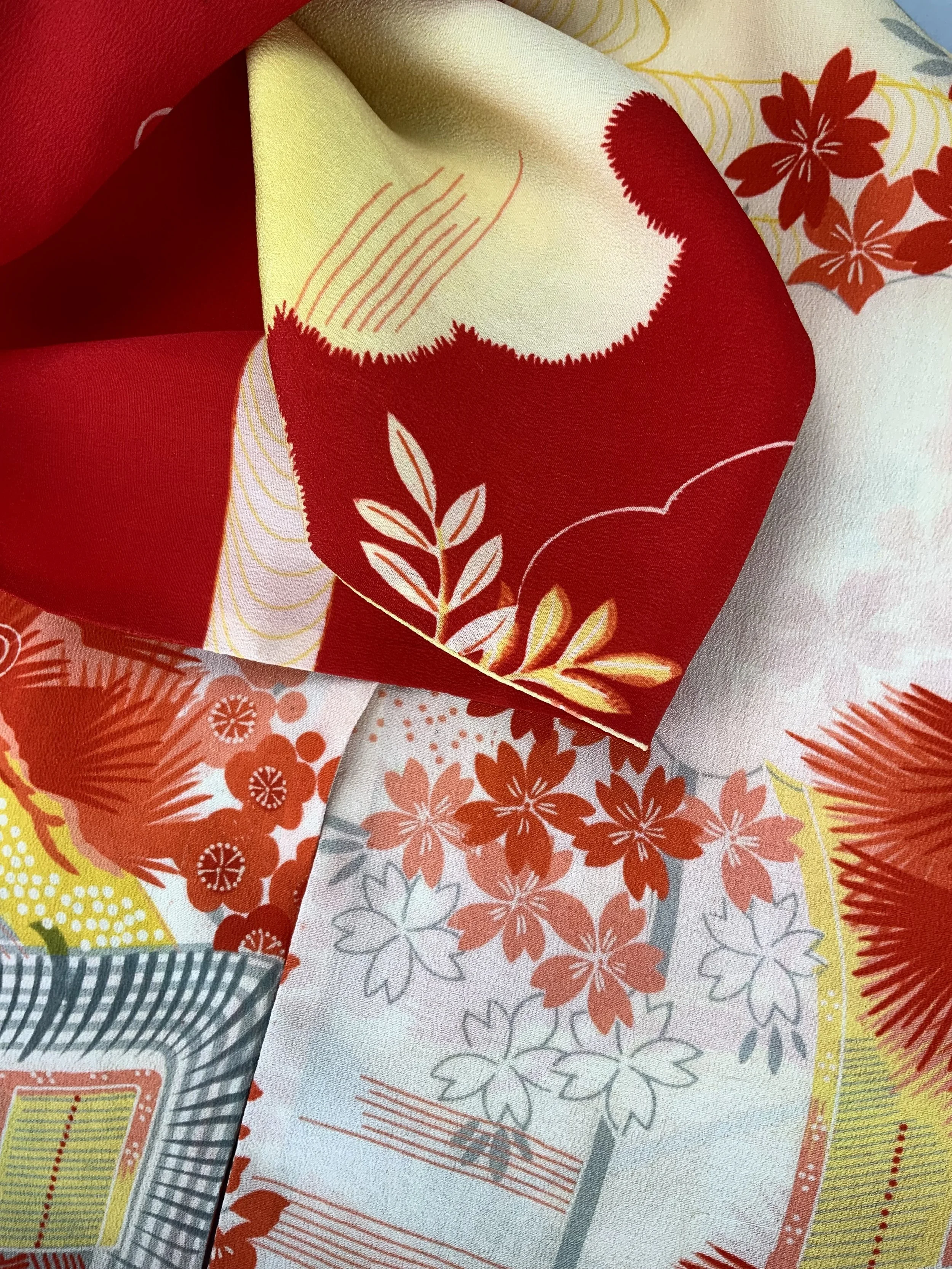 Closeup of vibrant red and yellow scarf with printed blossom design, handmade from repurposed Japanese kimono crepe silk by Kirsty Chivers