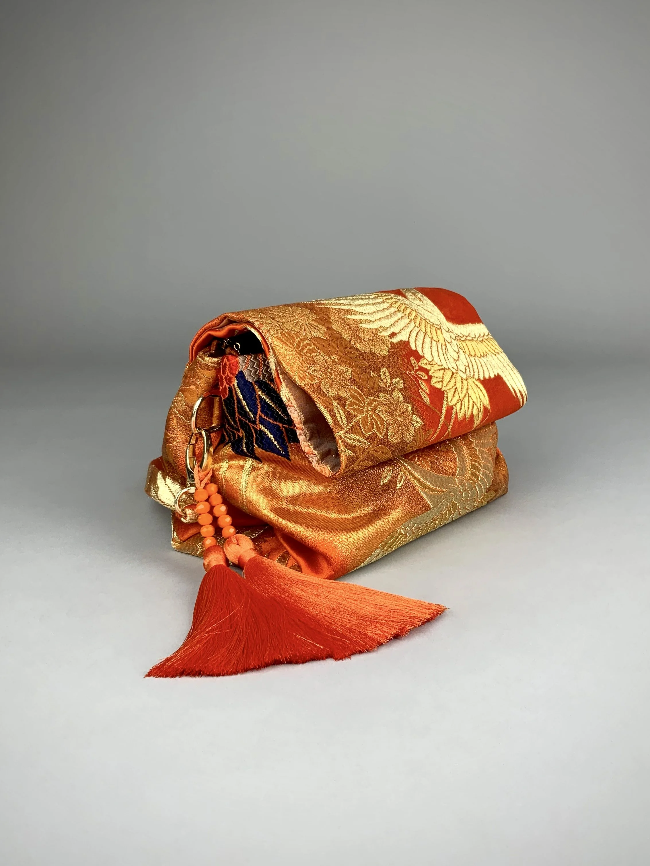 Vibrant orange evening bag with gold copper crane and blossom design, handmade from vintage obi silk by Kirsty Chivers