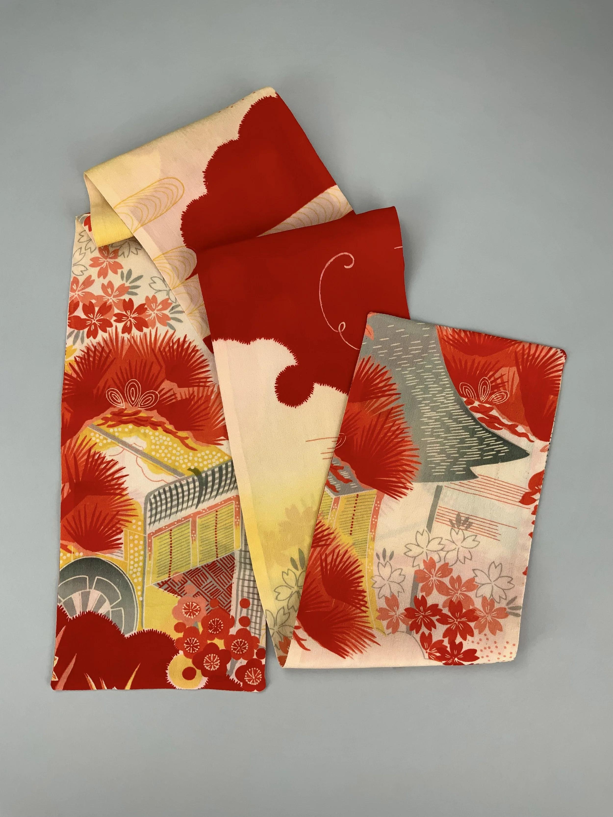 Flatlay of vibrant red and yellow scarf with printed blossom design, handmade from repurposed Japanese kimono crepe silk by Kirsty Chivers
