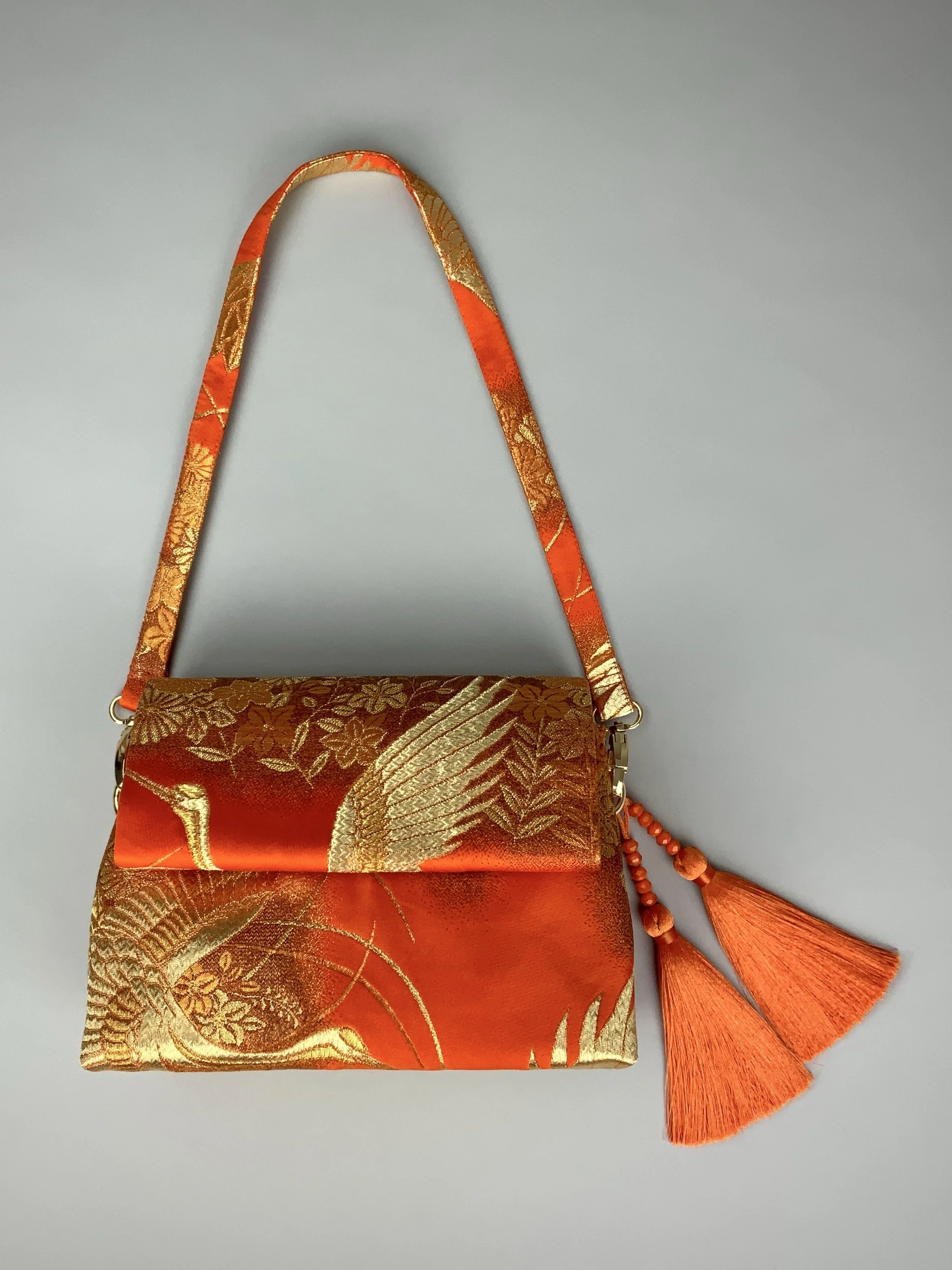 Vibrant orange evening bag with gold copper crane and blossom design, handmade from vintage obi silk by Kirsty Chivers