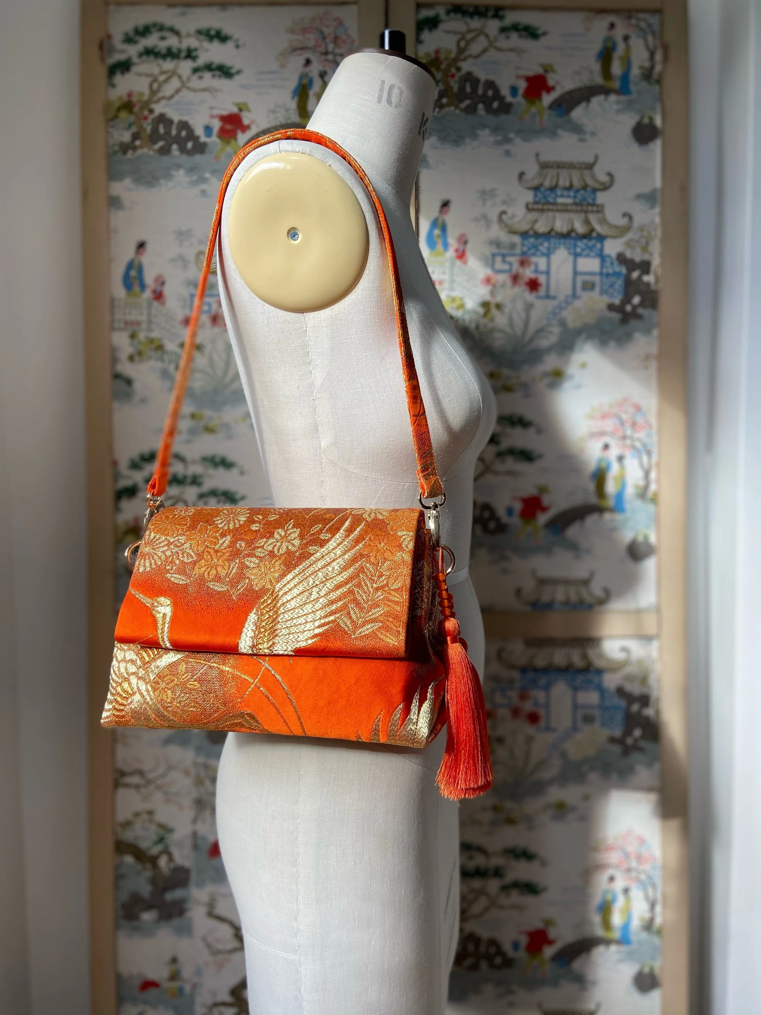 Vibrant orange evening bag with gold copper crane and blossom design, handmade from vintage obi silk by Kirsty Chivers