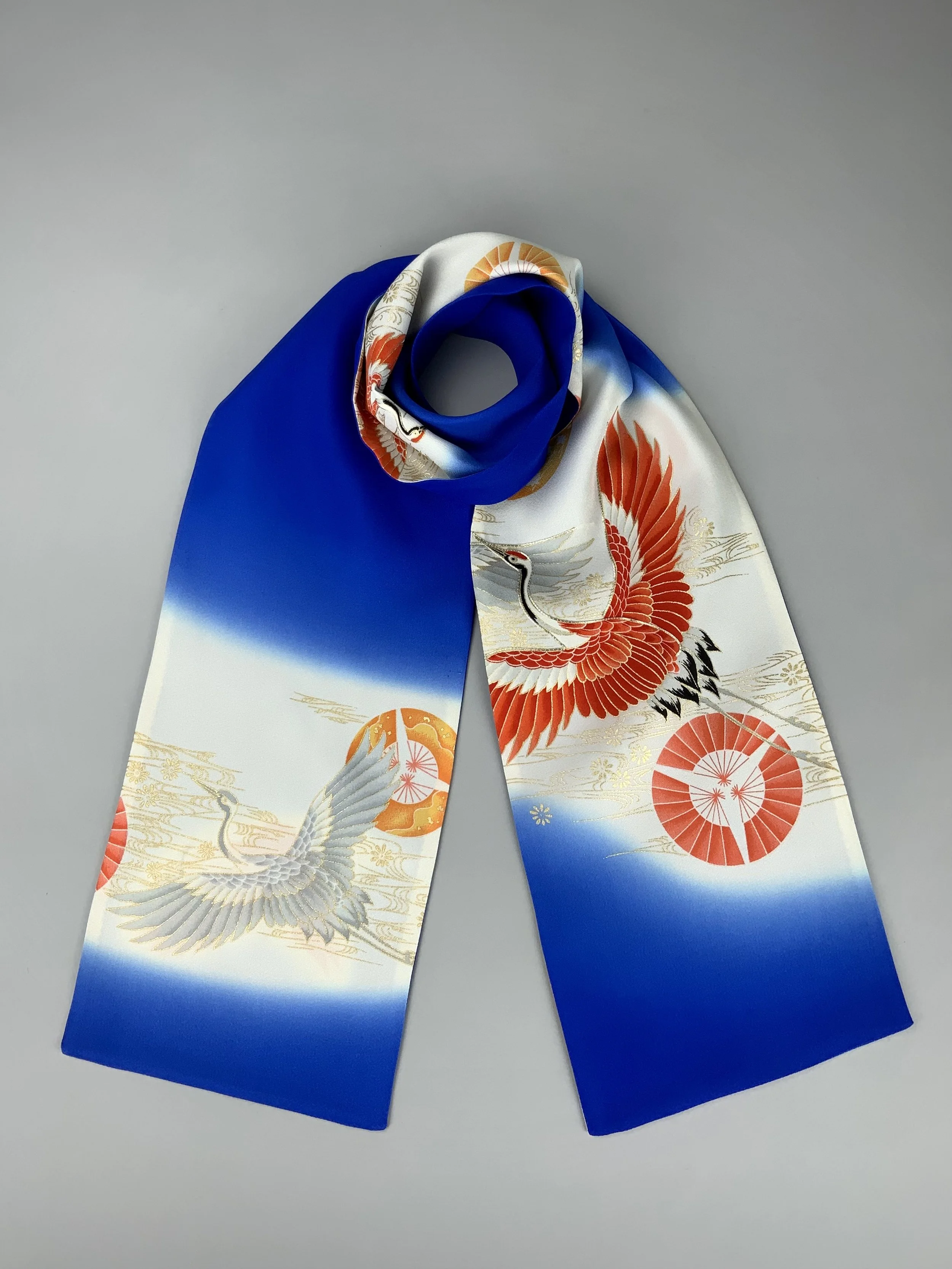 Flatlay of blue silk scarf with printed Flying Crane design handmade by Kirsty Chivers