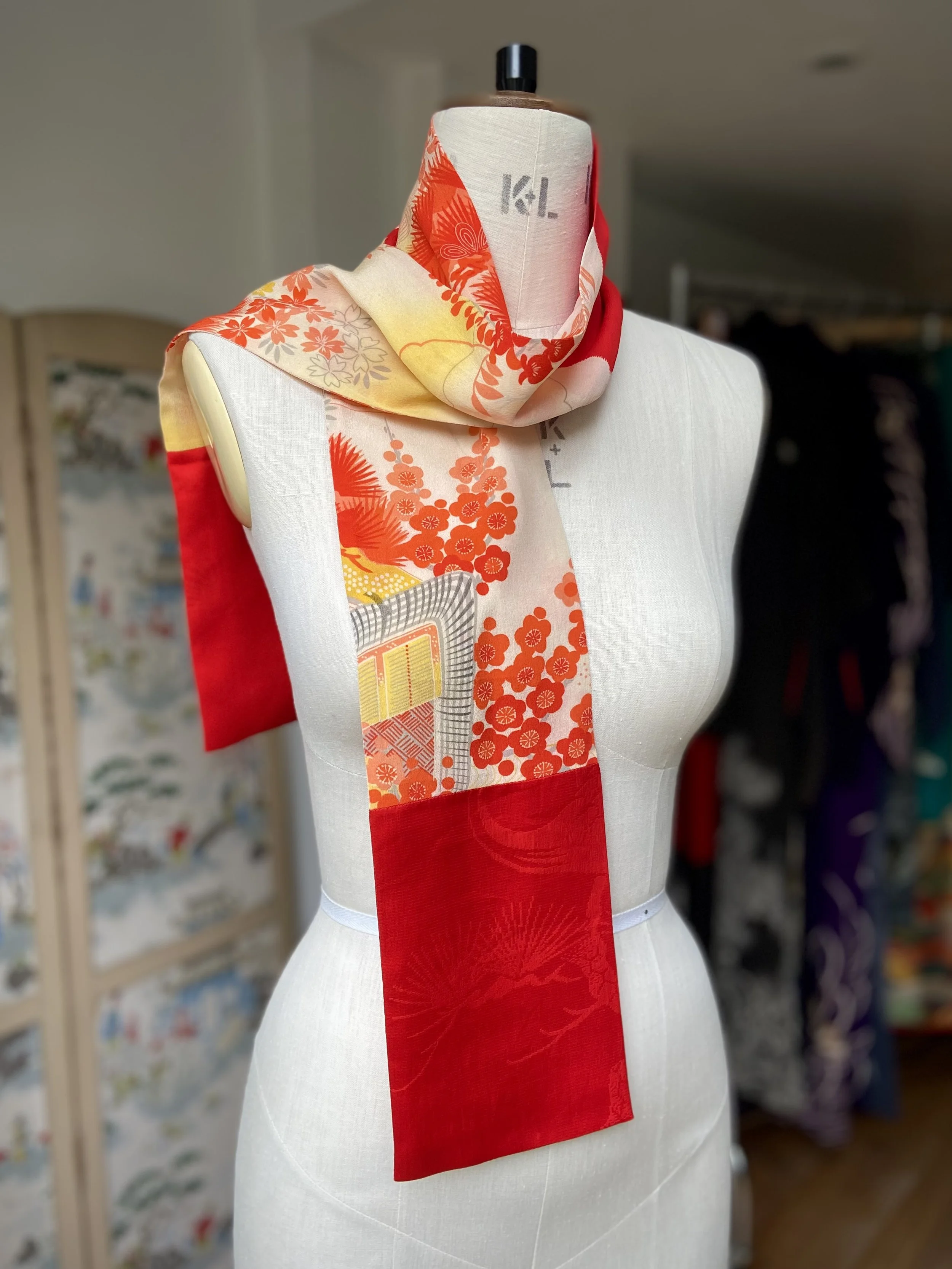 Bright red and yellow scarf presented on a dress stand, with printed blossom design, handmade from repurposed Japanese kimono crepe silk by Kirsty Chivers