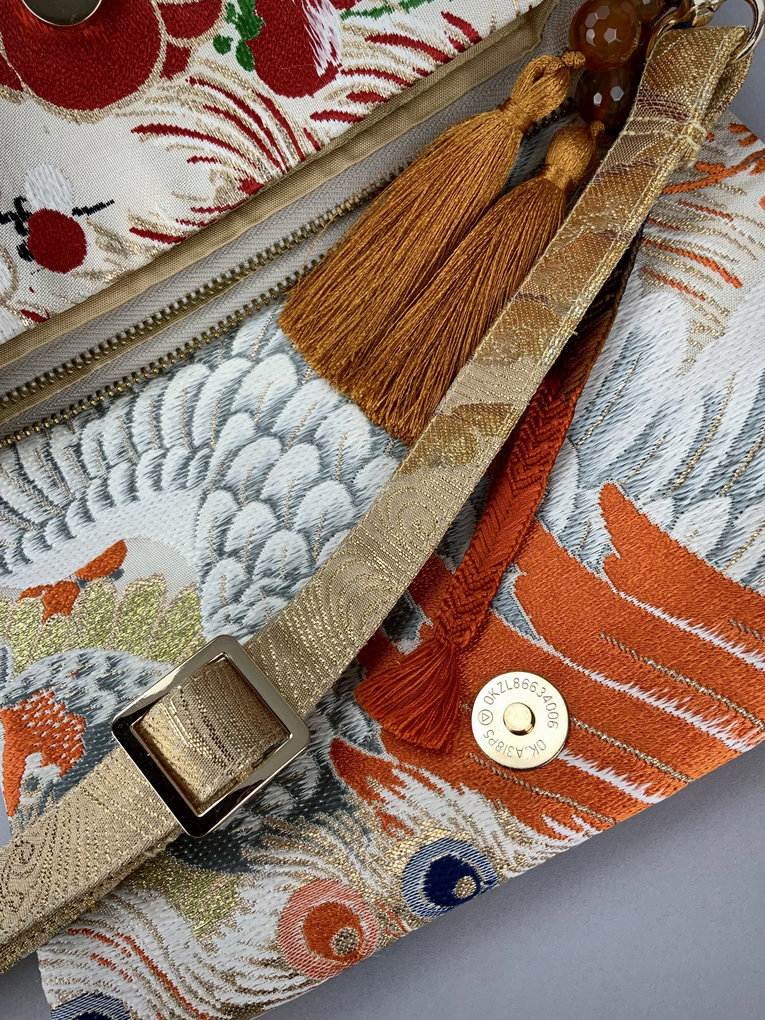 Closeup of one-of-a-kind evening bag in vintage obi silk with peacock, pine motifs & gold accents