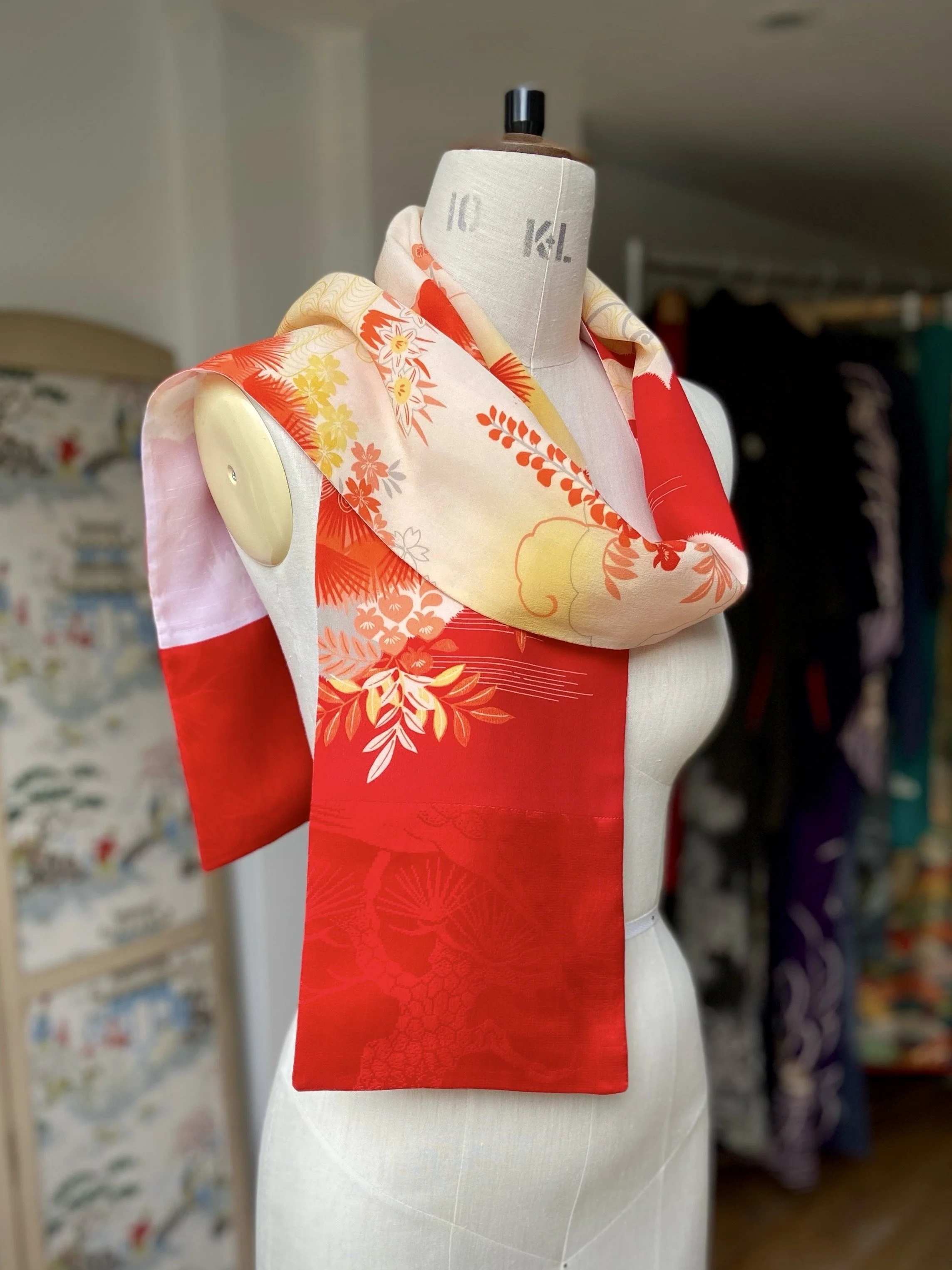 Bright vermillion red and yellow scarf presented on a dress stand, with printed blossom design, handmade from repurposed Japanese kimono crepe silk by Kirsty Chivers