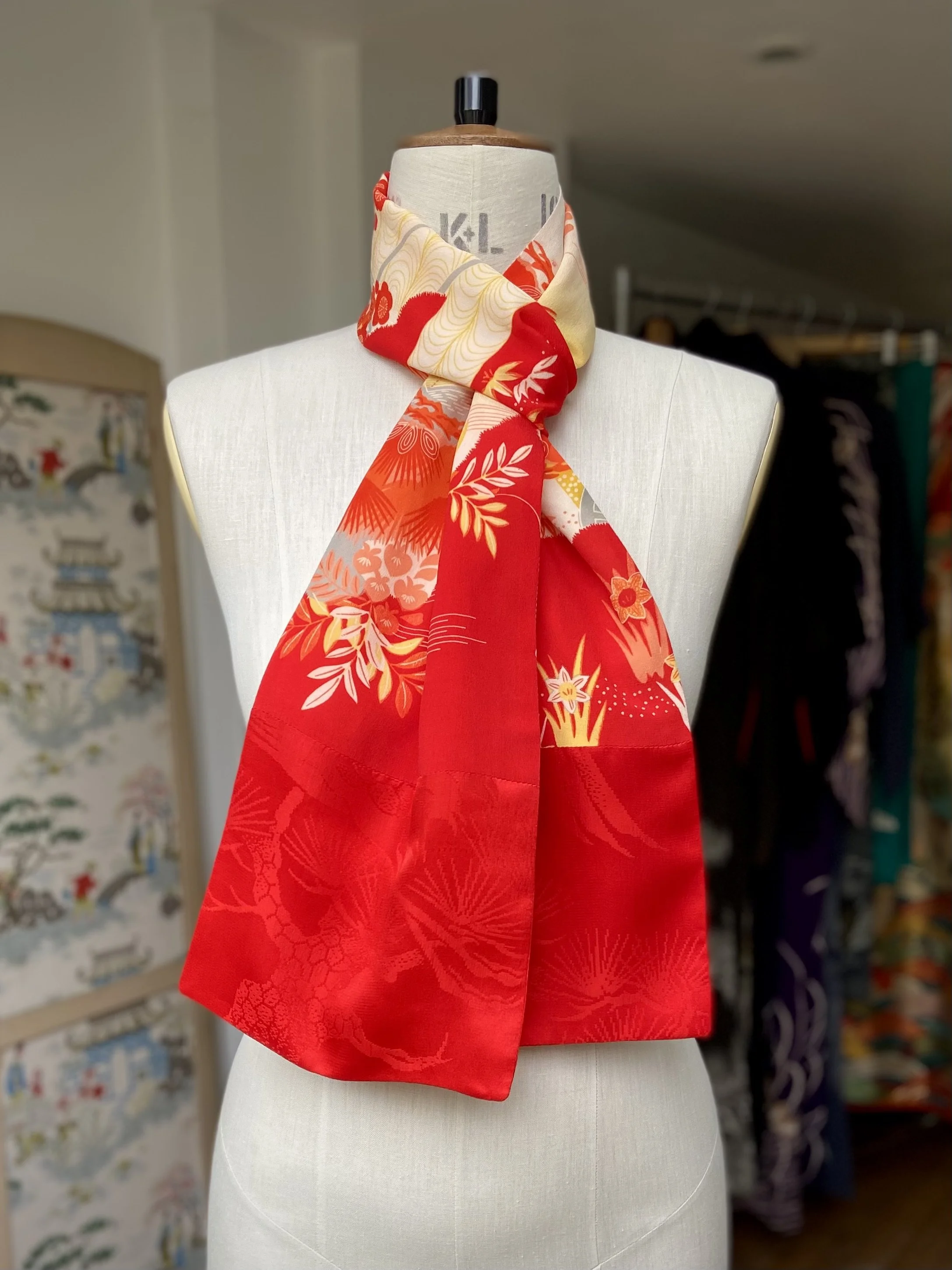 Bright vermillion red and yellow scarf presented on a dress stand, with printed blossom design, handmade from repurposed Japanese kimono crepe silk by Kirsty Chivers