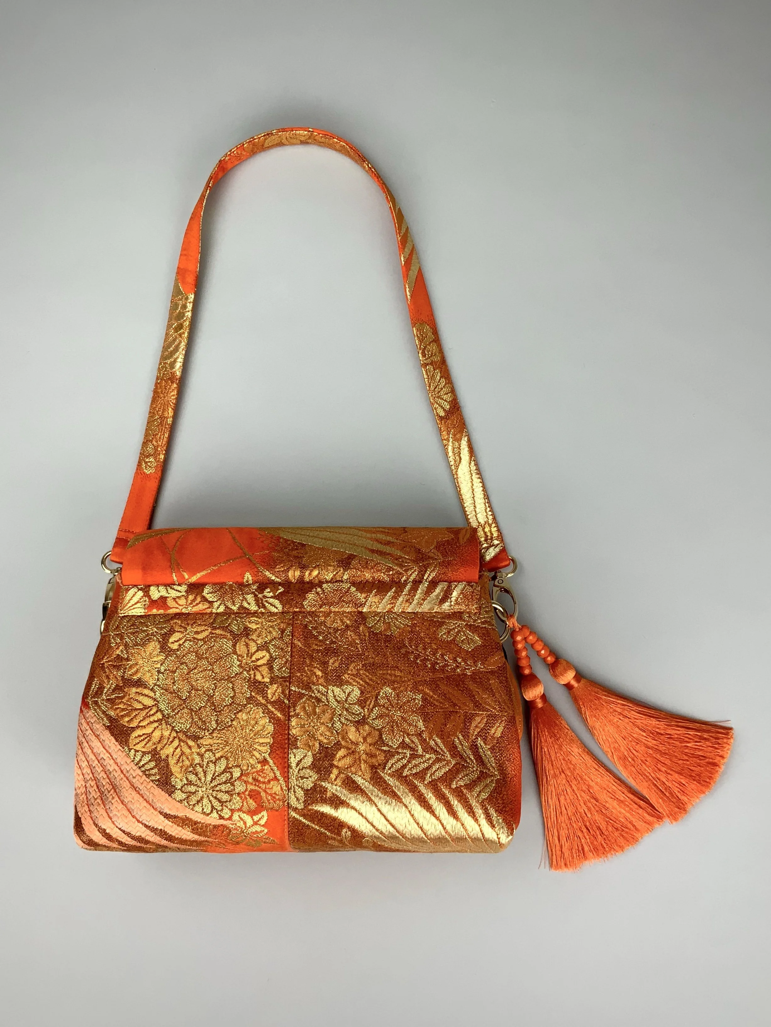 Vibrant orange evening bag with gold copper crane and blossom design, handmade from vintage obi silk by Kirsty Chivers