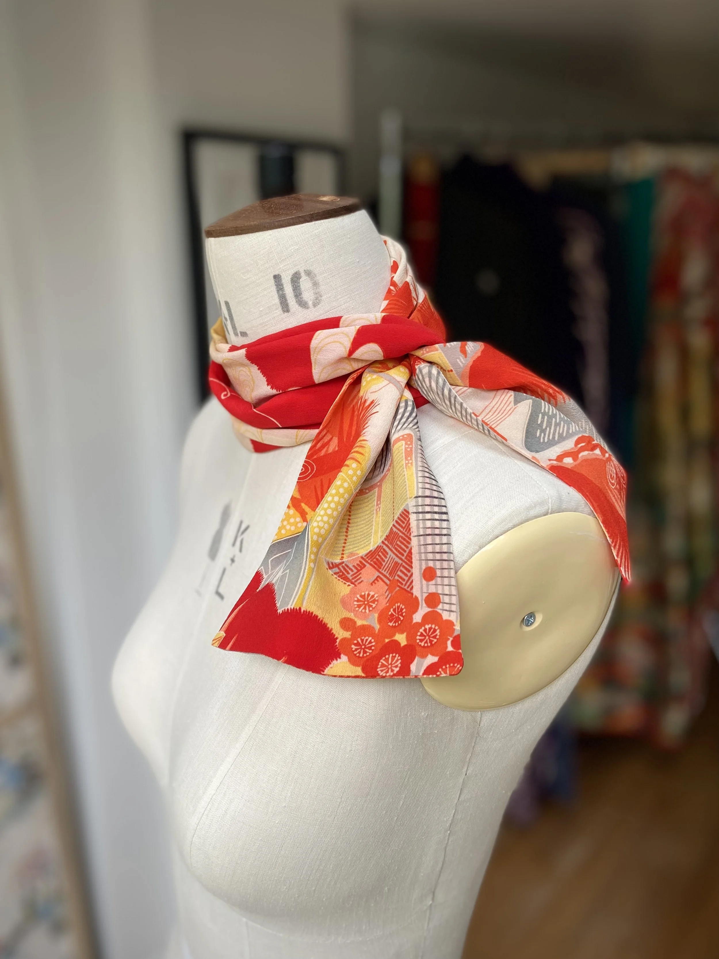Bright vermillion red and yellow scarf presented on a dress stand, with printed blossom design, handmade from repurposed Japanese kimono crepe silk by Kirsty Chivers
