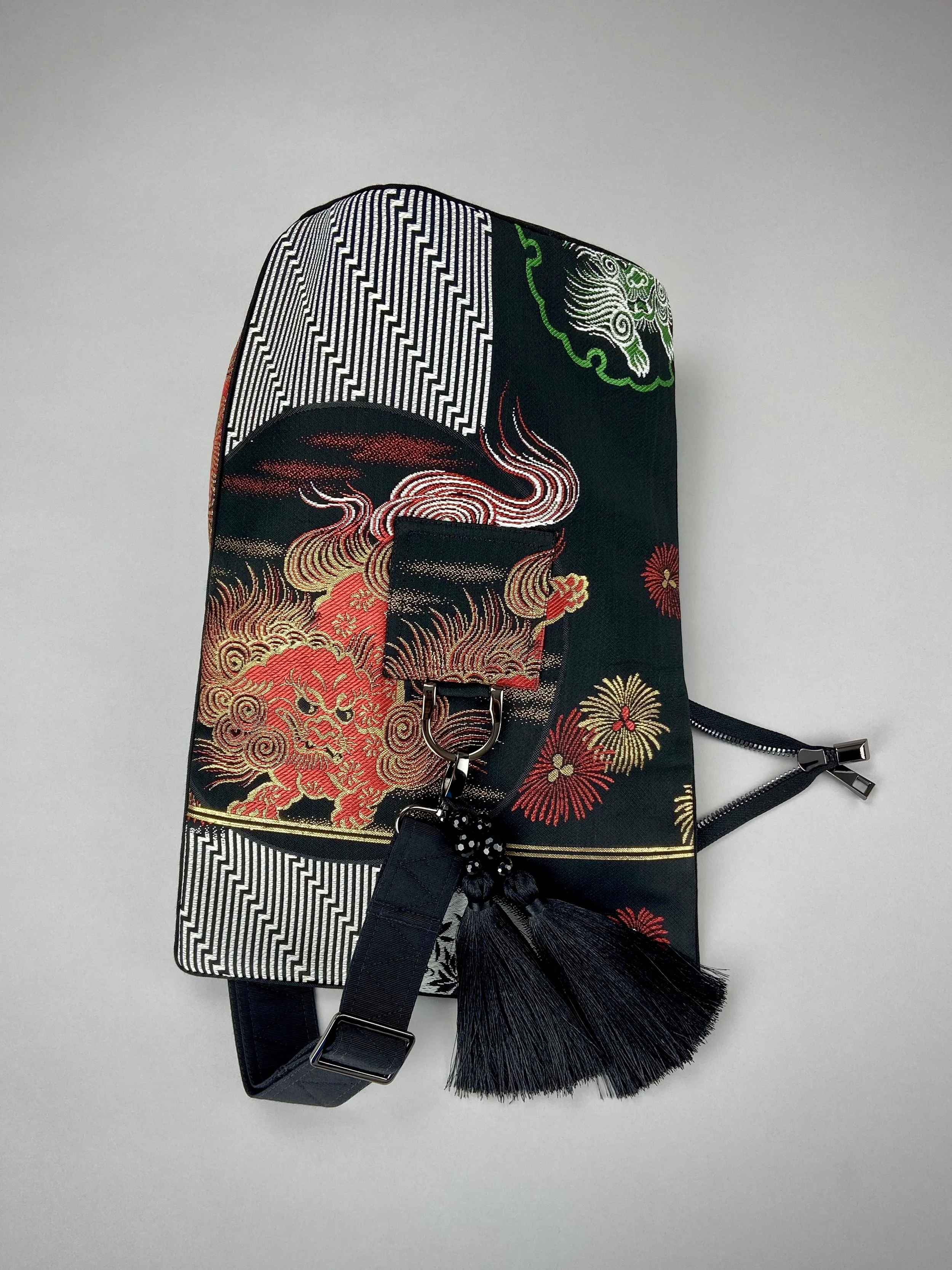 Black matt satin silk and rayon obi bag with red, green, gold and ivory dragon motifs, gunmetal hardware and black tassel charm by Kirsty Chivers