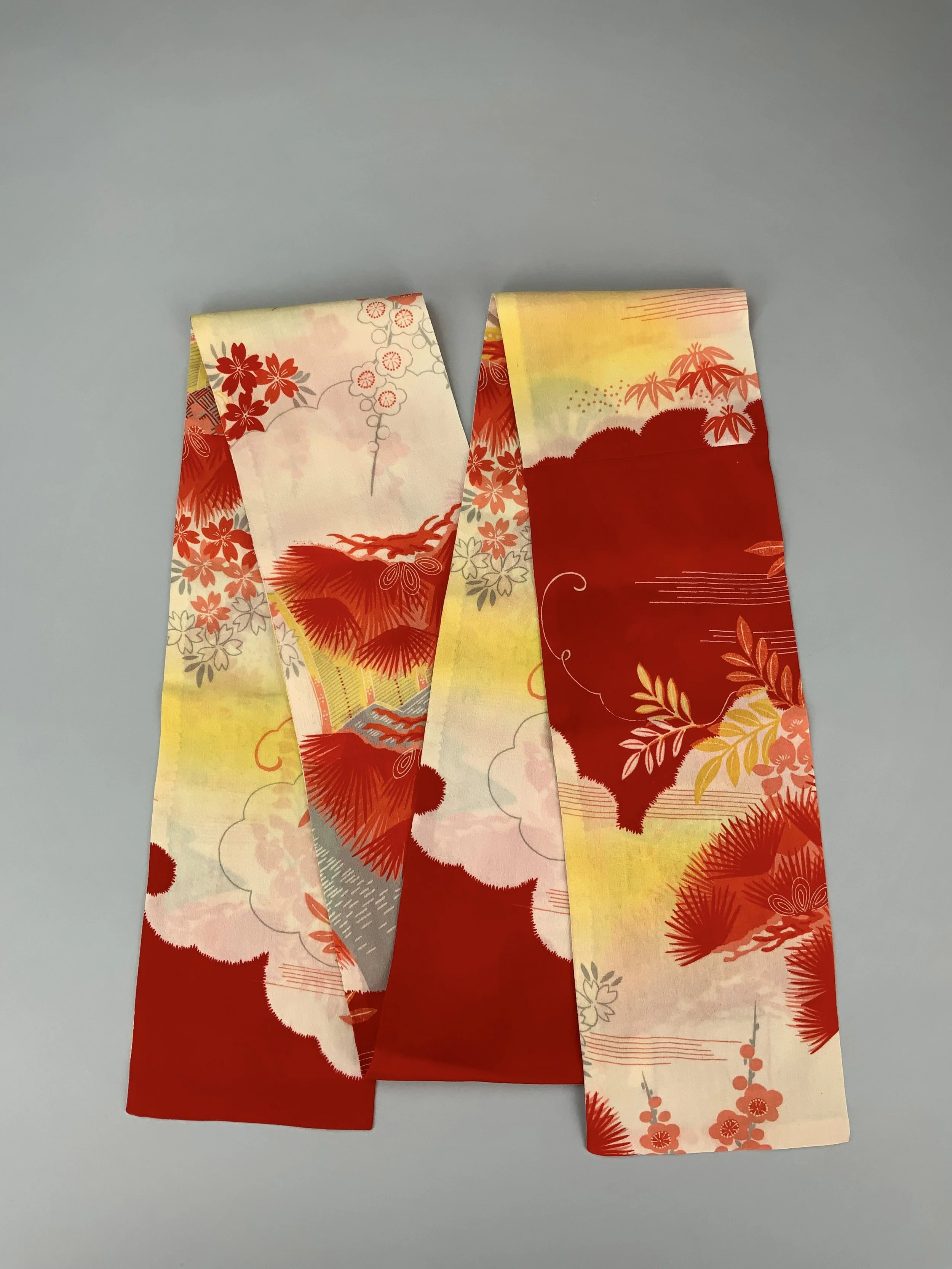 Flatlay of vibrant red and yellow scarf with printed blossom design, handmade from repurposed Japanese kimono crepe silk by Kirsty Chivers