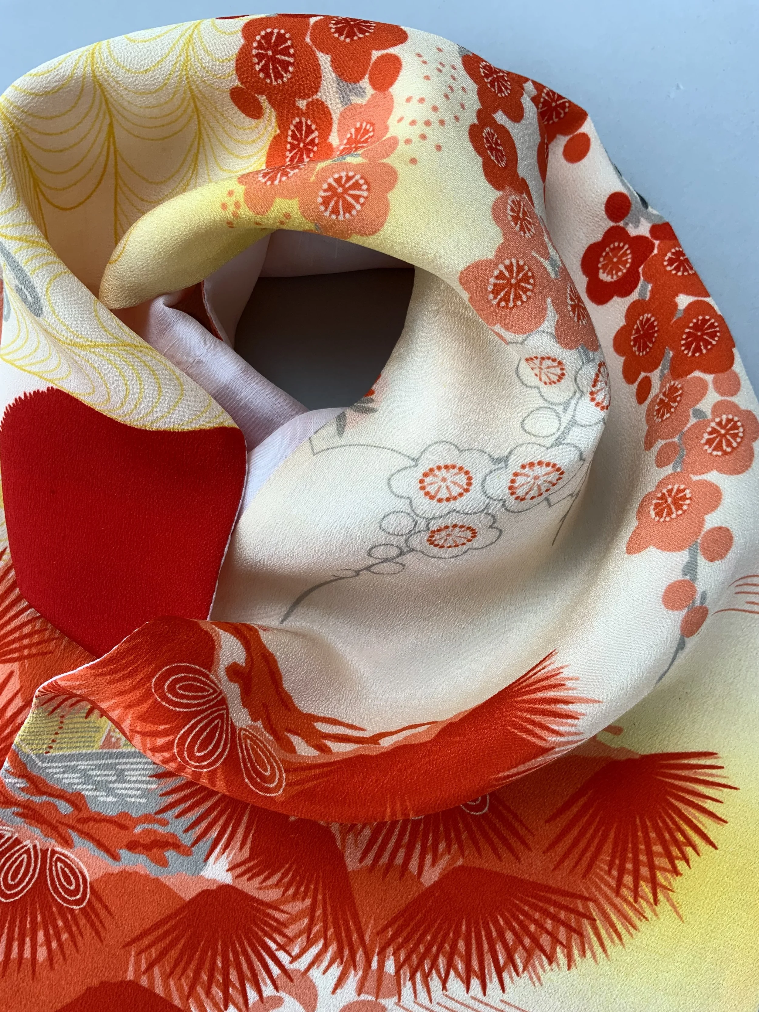 Closeup of vibrant red and yellow scarf with printed blossom design, handmade from repurposed Japanese kimono crepe silk by Kirsty Chivers