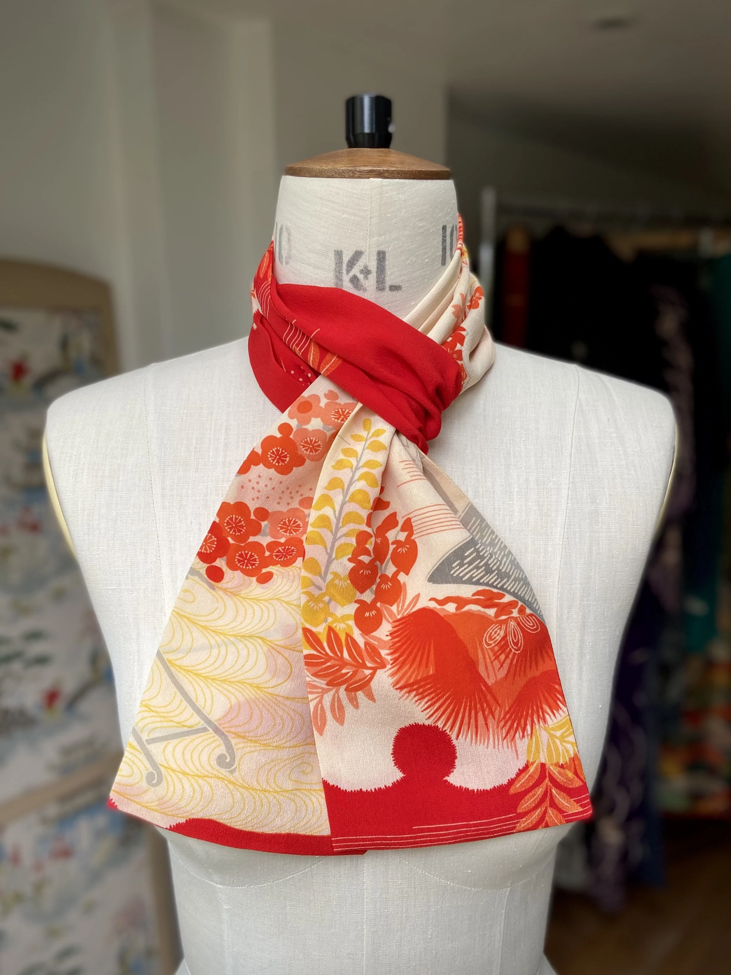 Bright vermillion red and yellow scarf presented on a dress stand, with printed blossom design, handmade from repurposed Japanese kimono crepe silk by Kirsty Chivers