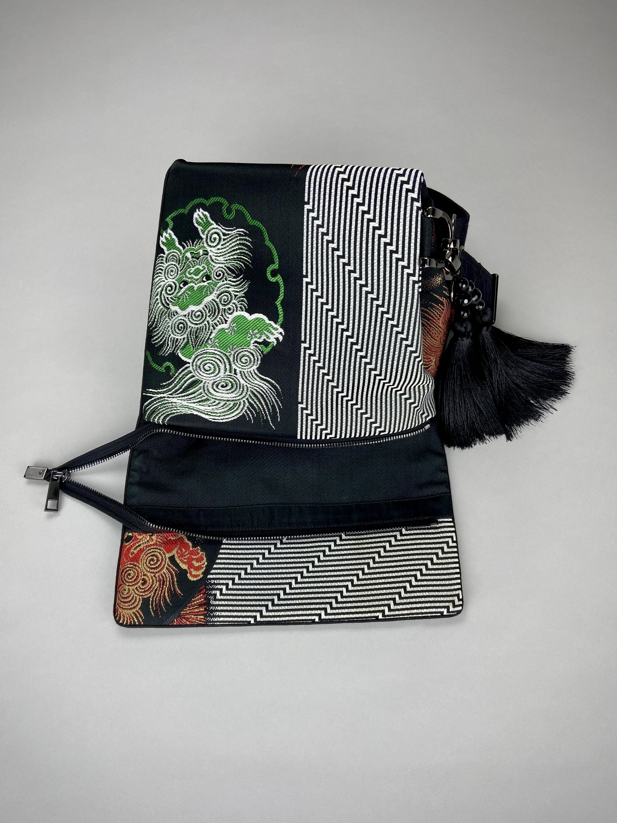 Black matt satin silk and rayon obi bag with red, green, gold and ivory dragon motifs, gunmetal hardware and black tassel charm by Kirsty Chivers