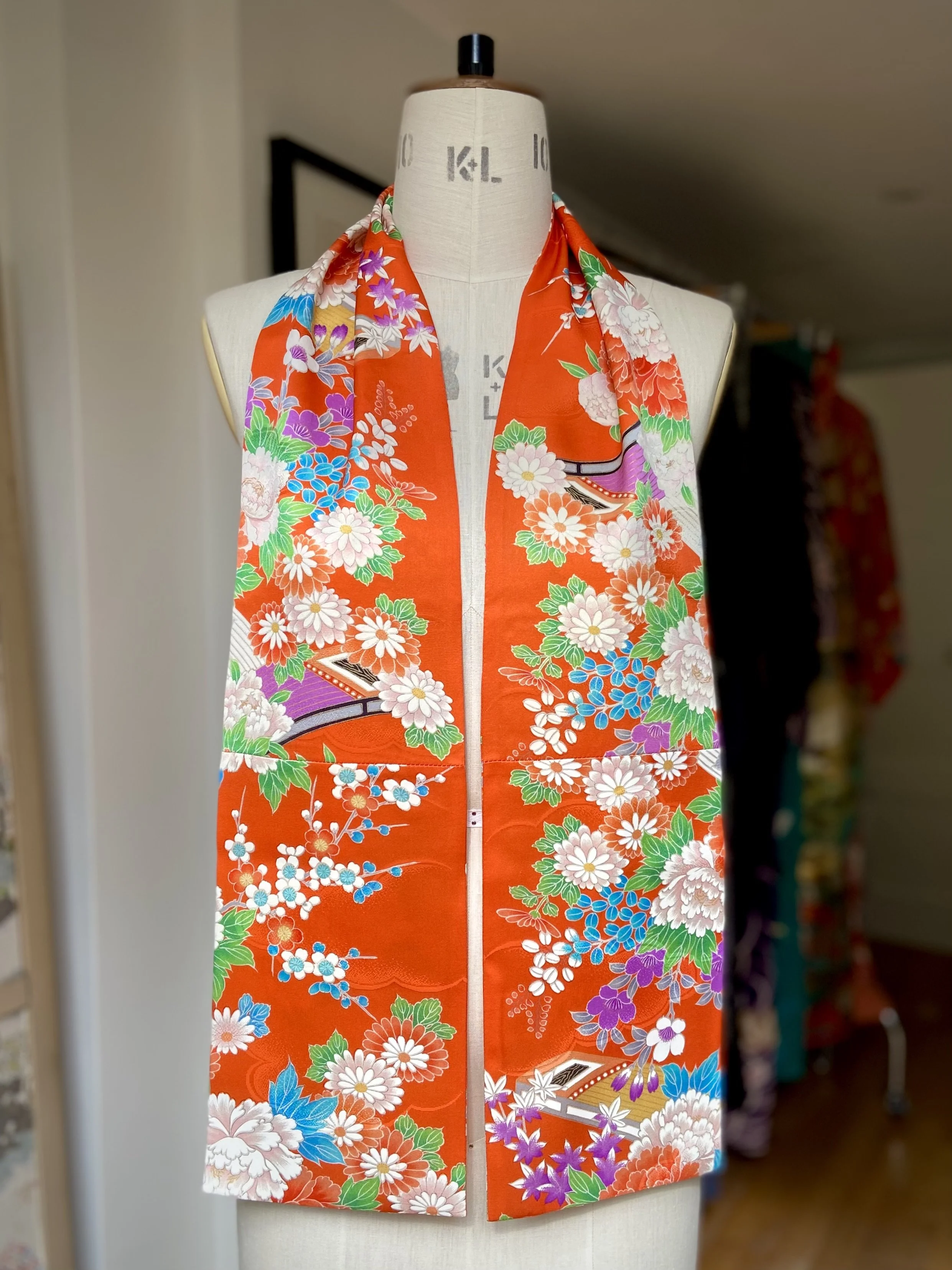 Orange scarf presented on a dress stand. It has a blossom print and is made from rinzu kimono silk by Kirsty Chivers