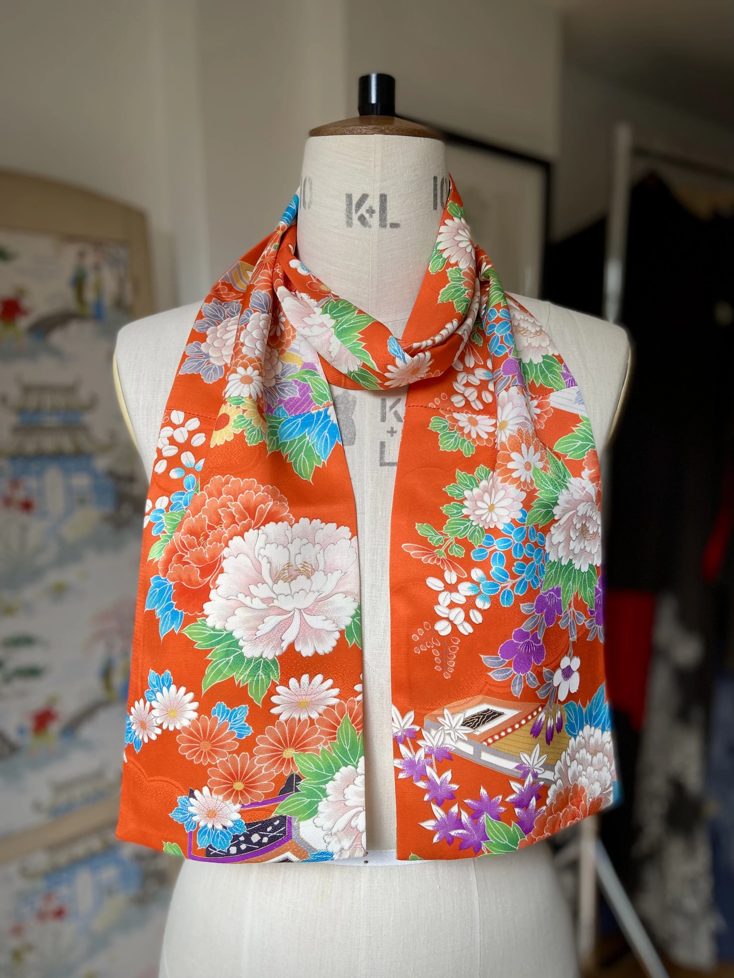 Orange scarf presented on a dress stand. It has a blossom print and is made from rinzu kimono silk by Kirsty Chivers