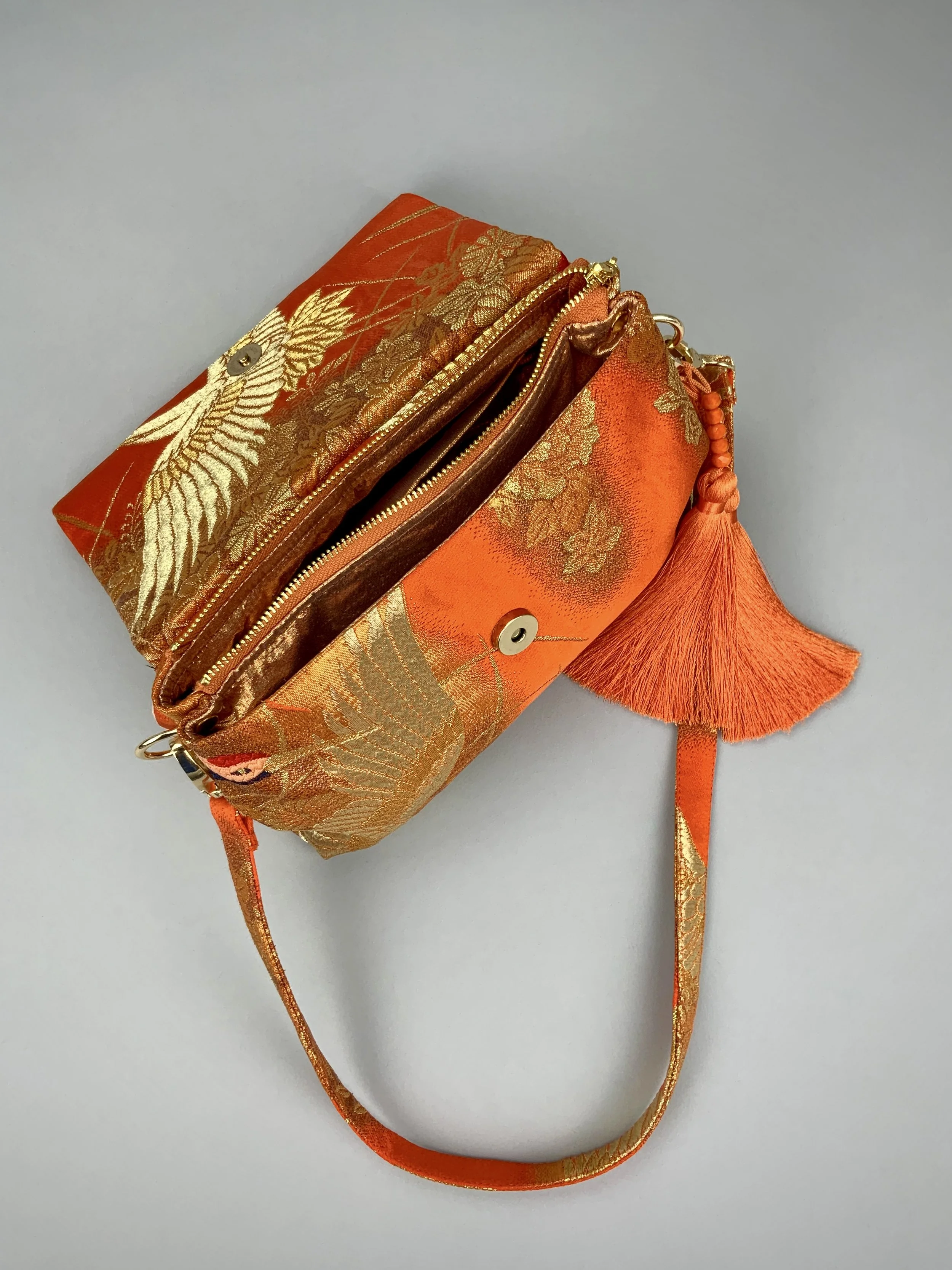 Vibrant orange evening bag with gold copper crane and blossom design, handmade from vintage obi silk by Kirsty Chivers