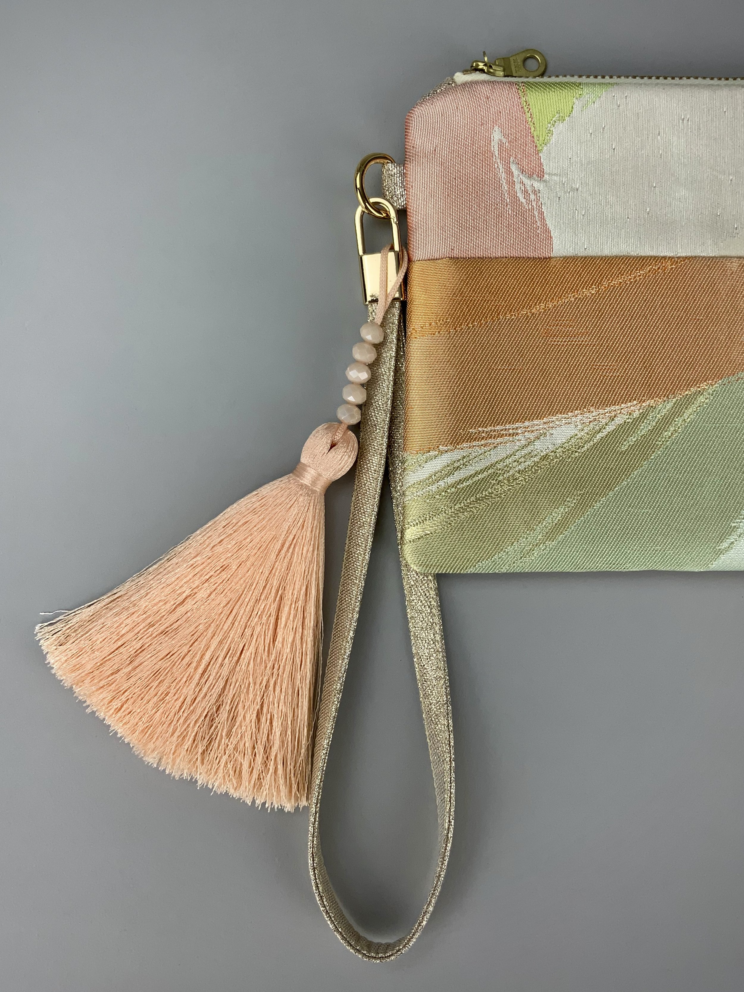 Closeup of wristlet purse made from repurposed vintage obi fabric with brushstroke pastel design and gold-silver threads