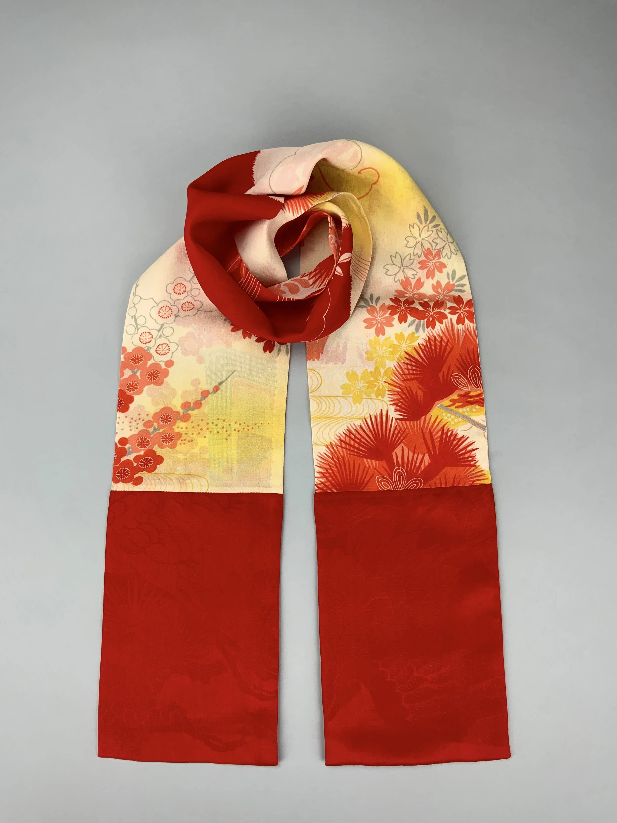 Flatlay of vibrant red and yellow scarf with printed blossom design, handmade from repurposed Japanese kimono crepe silk by Kirsty Chivers