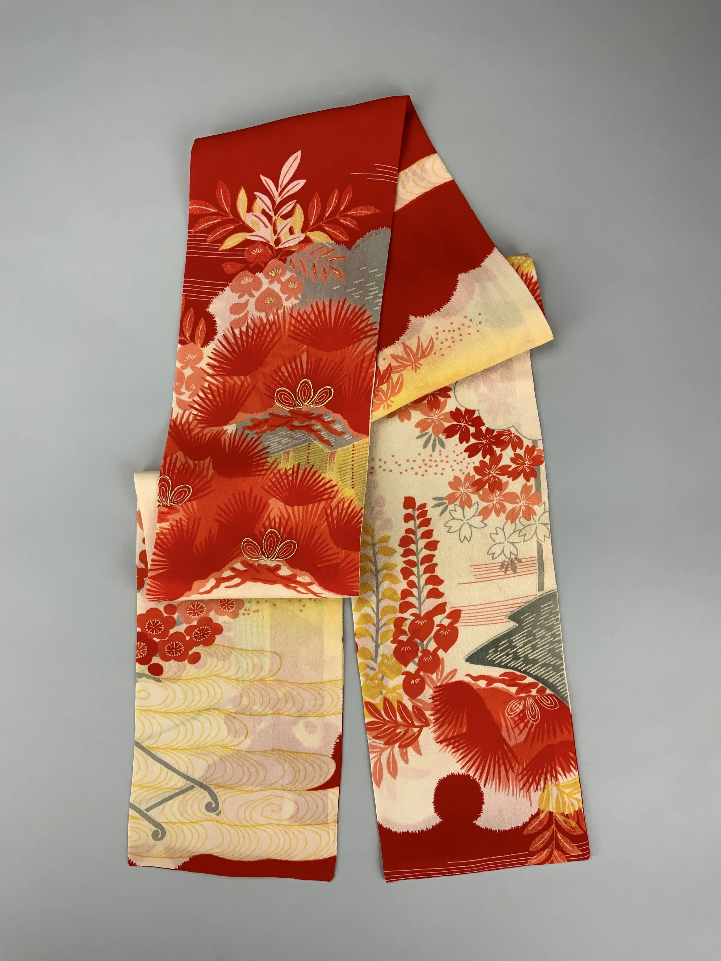 Flatlay of vibrant red and yellow scarf with printed blossom design, handmade from repurposed Japanese kimono crepe silk by Kirsty Chivers